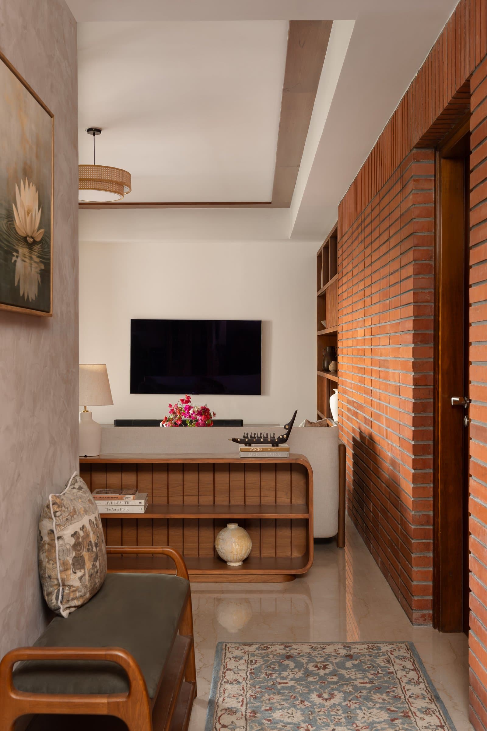 The foyer-to-living transition: exposed brick and rounded timber joinery establish the home's material argument before the room fully begins