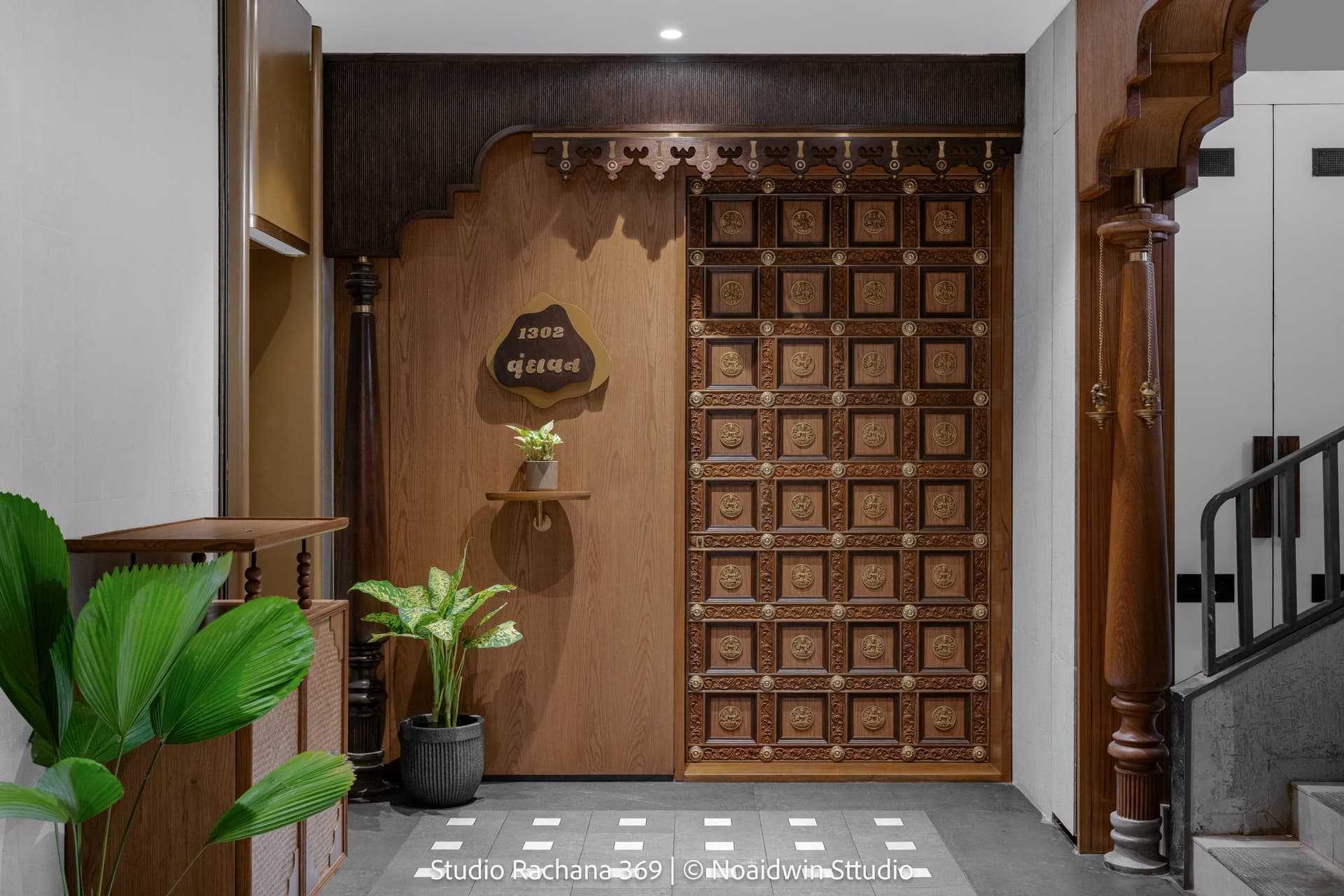 The entrance to Wing A: a carved teak door with medallion panels, flanked by turned timber columns, sets the tone before the threshold is crossed