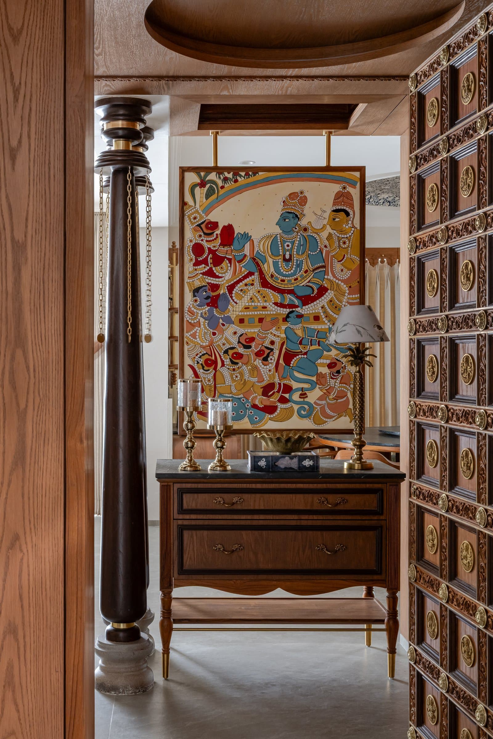 Through the open door, a Kalamkari-style painting and a stone-topped console establish the foyer's narrative register