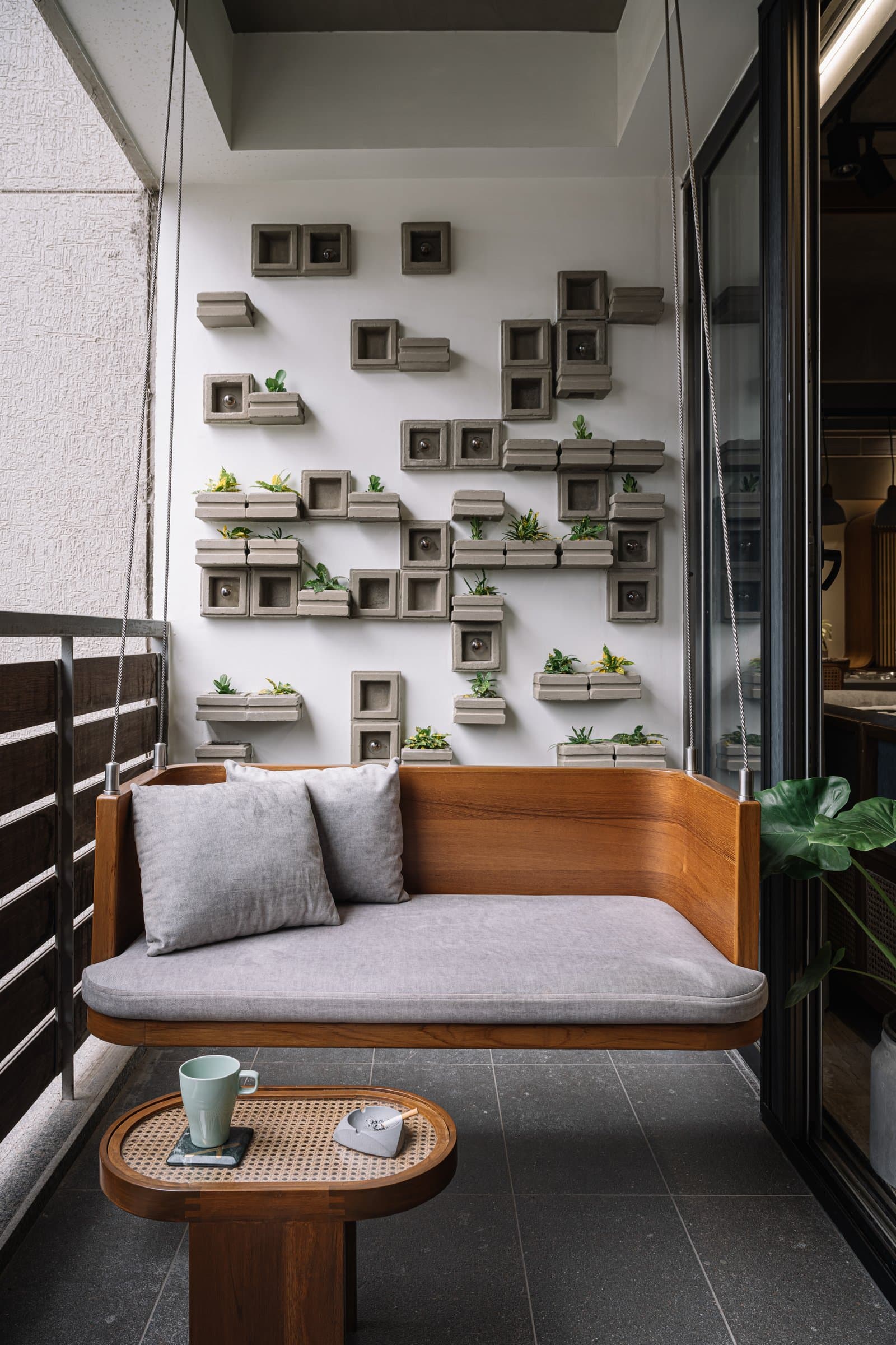 The balcony's modular concrete planter wall and timber swing seat, the home's quietest corner