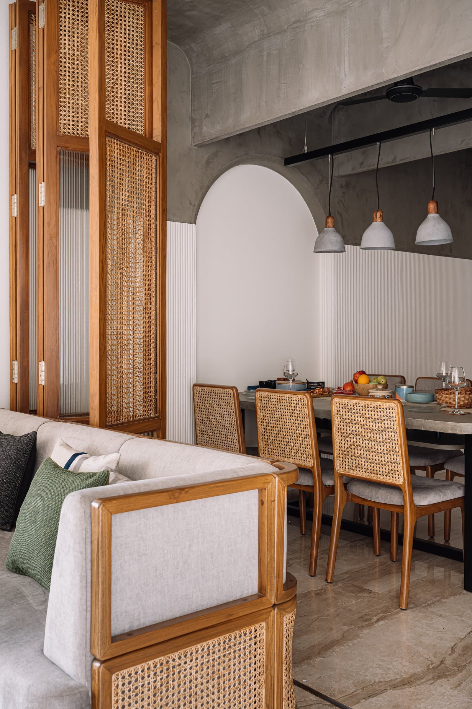 Living and dining in conversation: layered planes of cane, timber, and upholstery create visual depth across the open plan