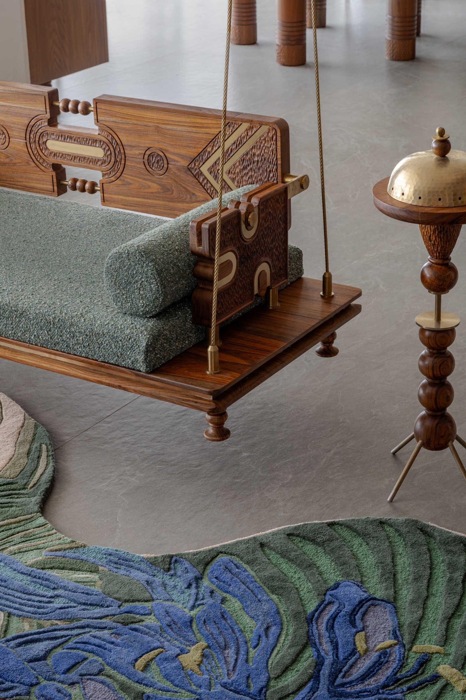 The carved timber jhula beside a hammered brass incense stand, Gujarat's domestic ritual suspended at the thirteenth floor