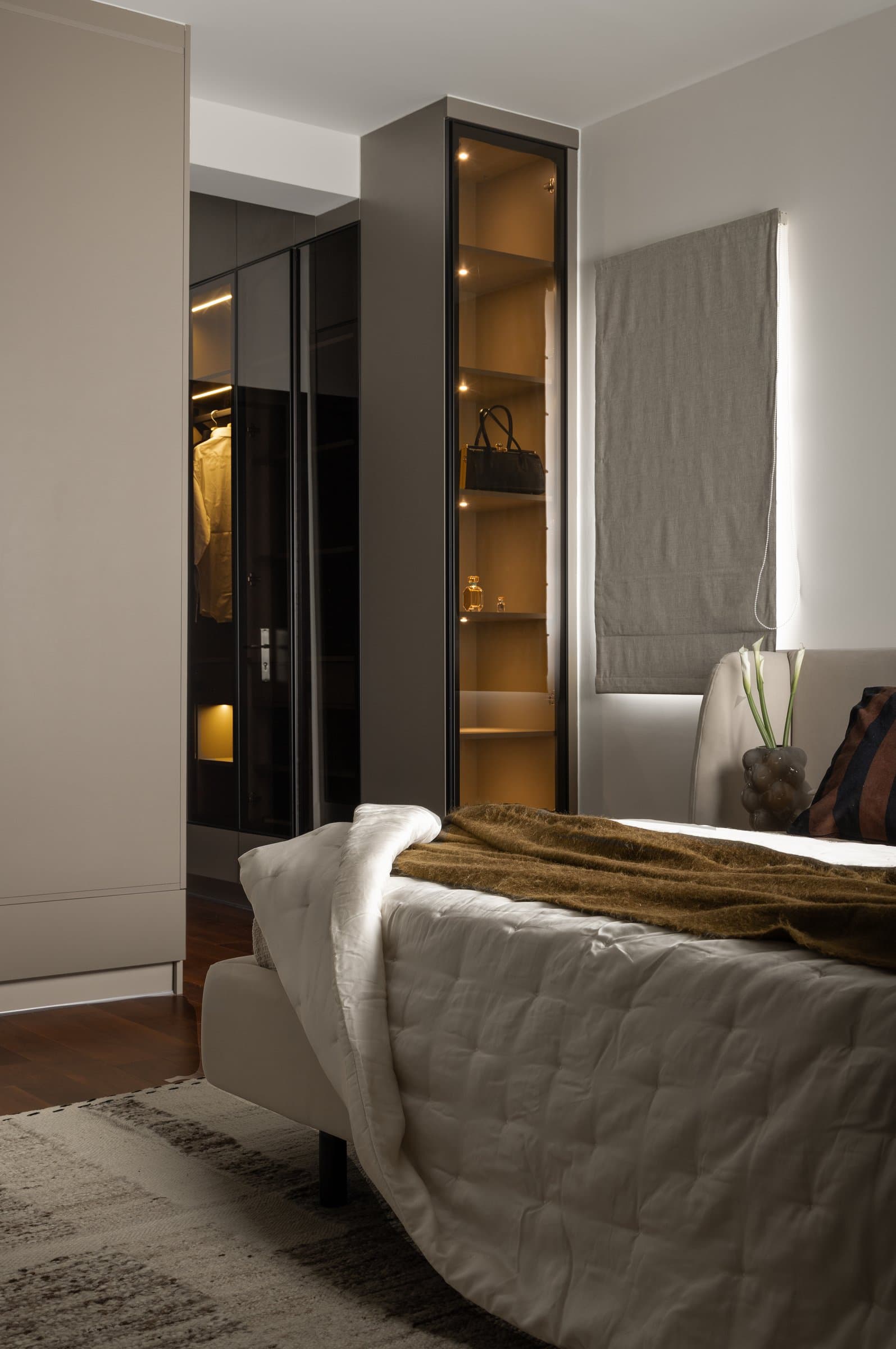 Glass-fronted wardrobes in the master bedroom, reducing visual mass while lending warmth through interior lighting