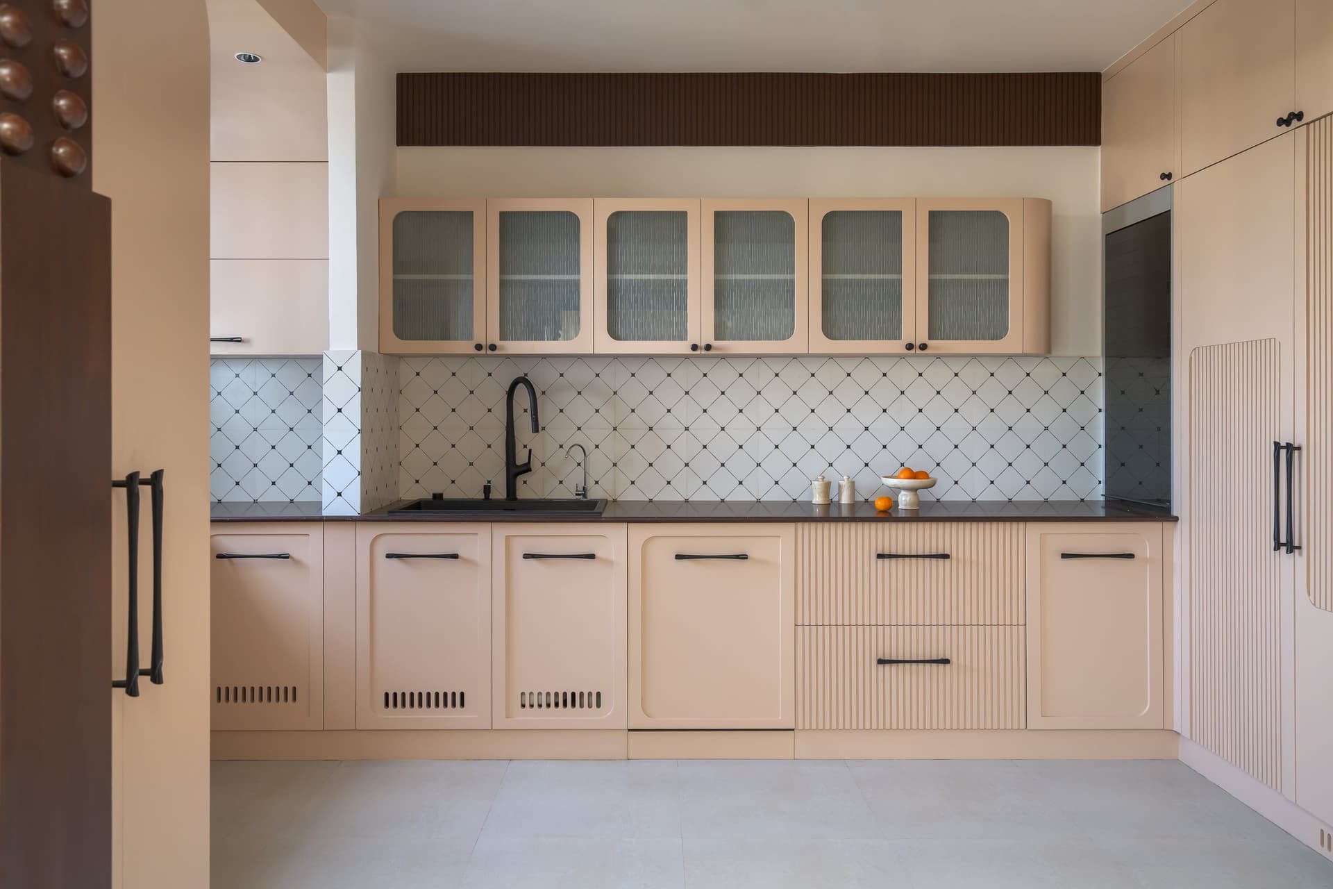 The kitchen, where arched cabinet panels and a diamond-patterned backsplash carry the curved vocabulary into a more restrained register