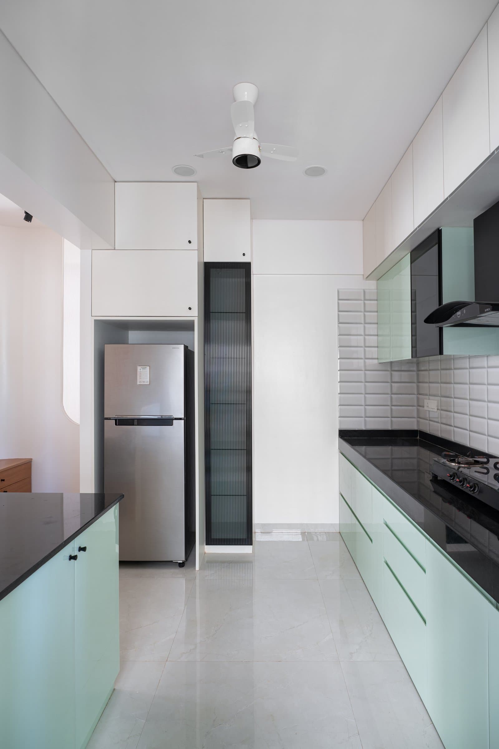 Inside the kitchen, where the parallel layout and a tall fluted-glass display unit maximise a narrow footprint