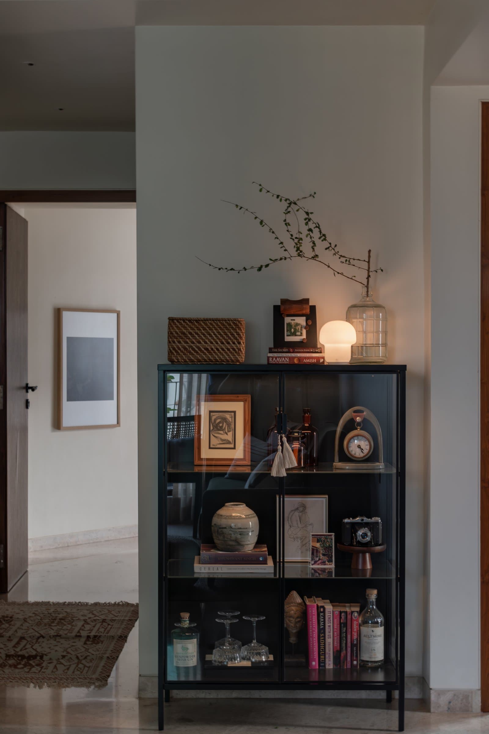 A black-framed vitrine in the living area, treated less as storage than as a quiet portrait of the people who live here