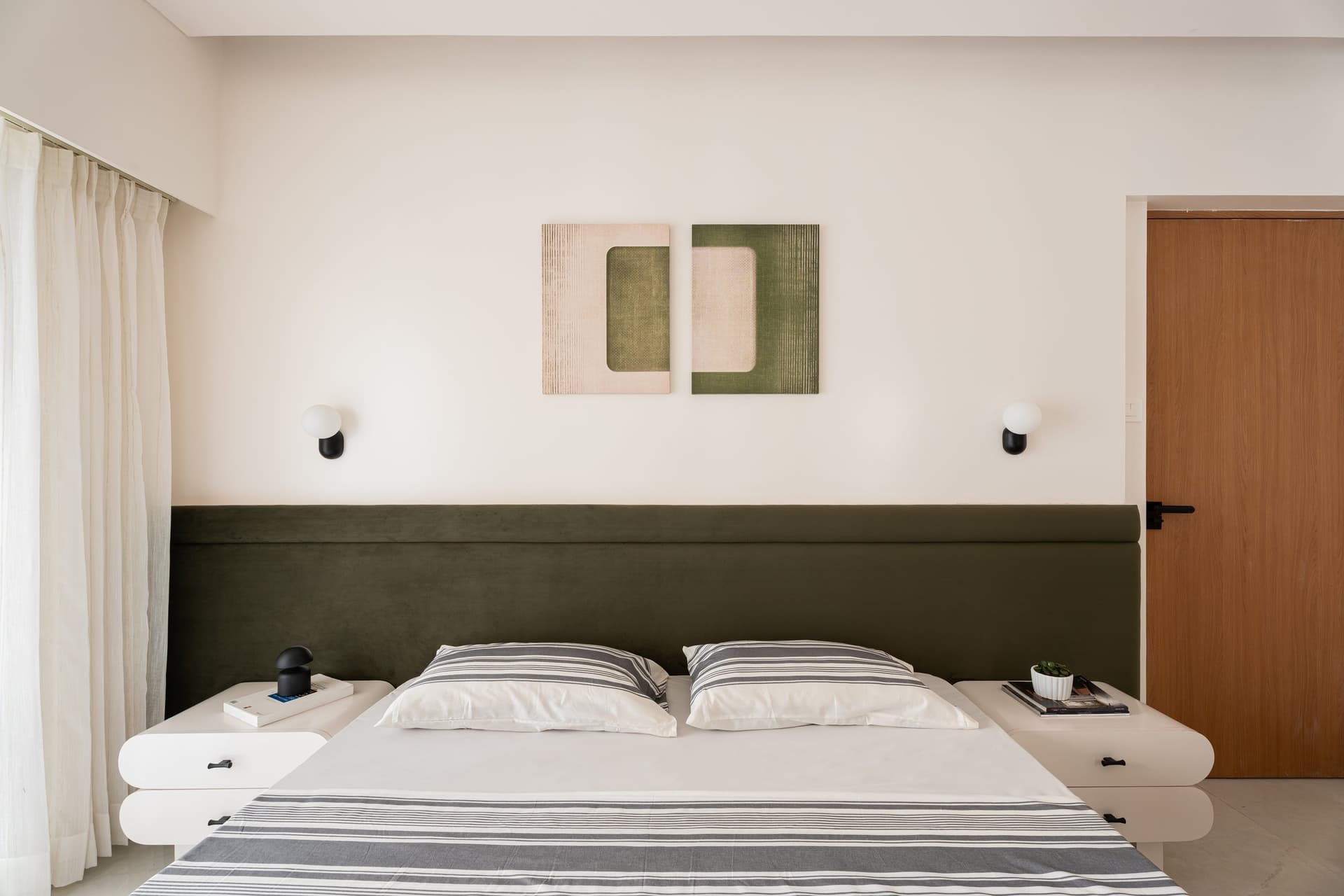 The master bedroom, anchored by an olive-green headboard that stretches the full width of the wall
