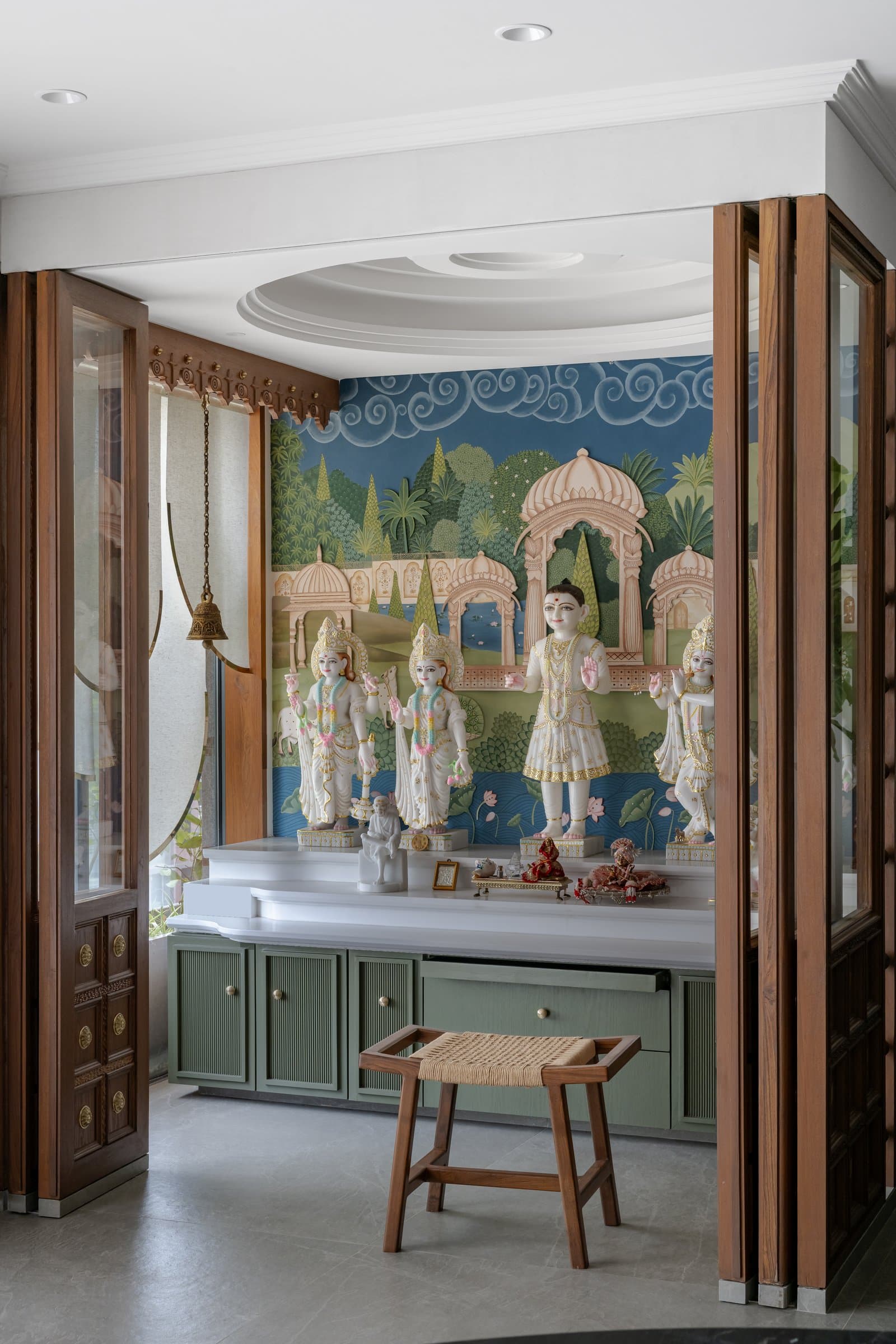 The Ram Darbar pooja room in Wing A, where a hand-painted pichwai mural wraps marble deities on a white plinth