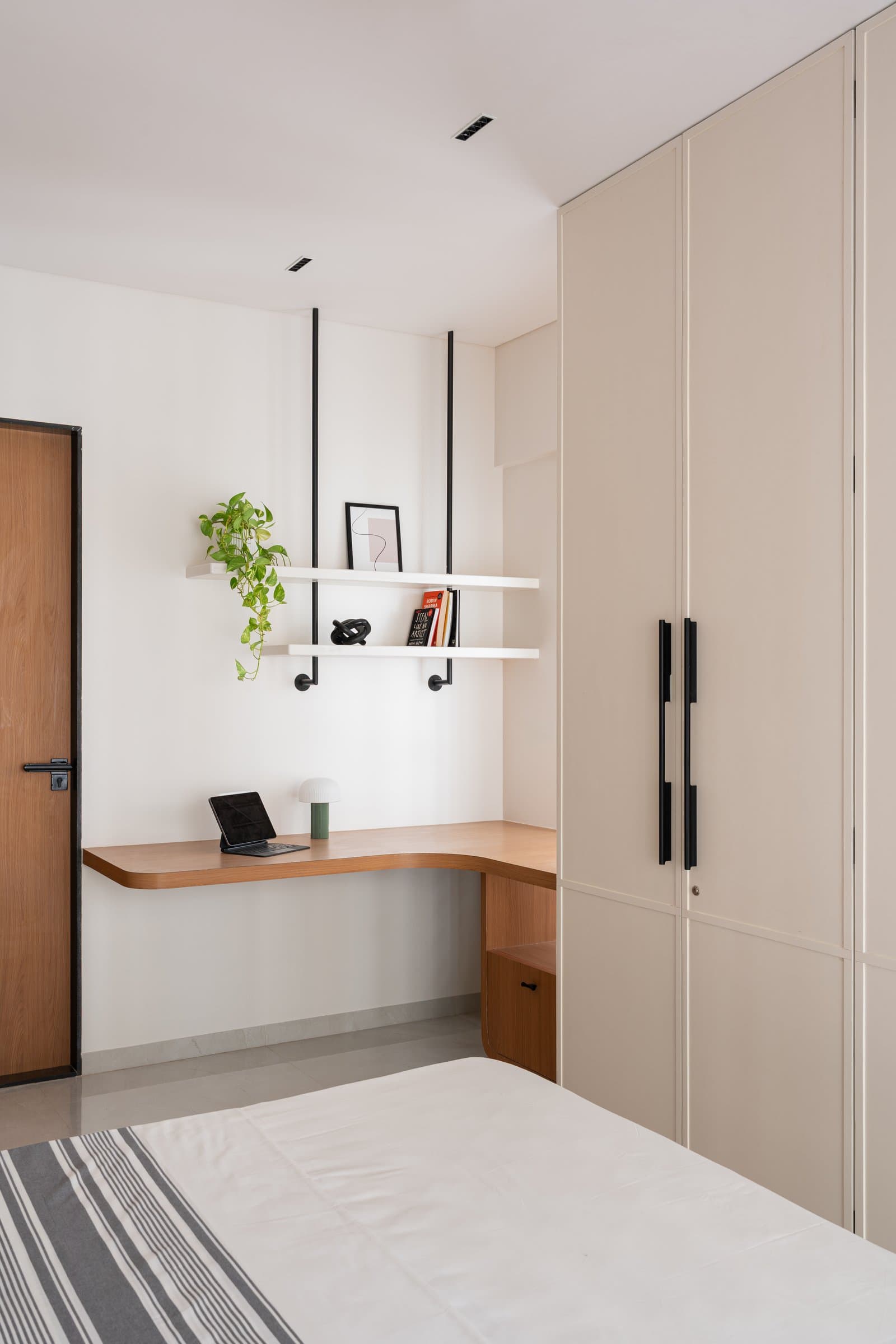 A built-in study nook with a curving timber desk and suspended shelving completes the second bedroom