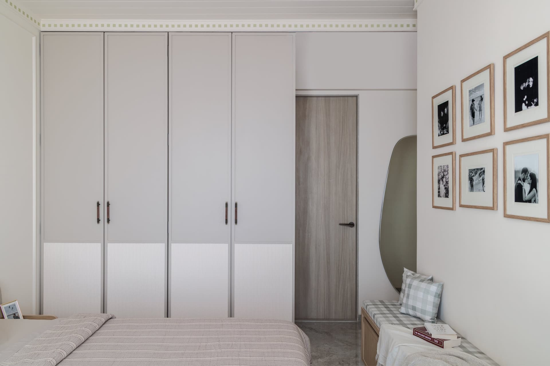 The wardrobe wall and a gallery of black-and-white photographs, personal warmth held within architectural restraint