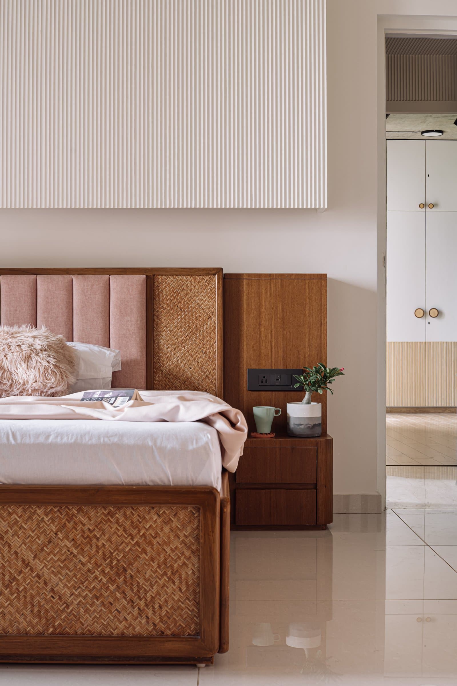 The parents' bedroom: a woven-cane bed frame and blush headboard in the home's warmest palette