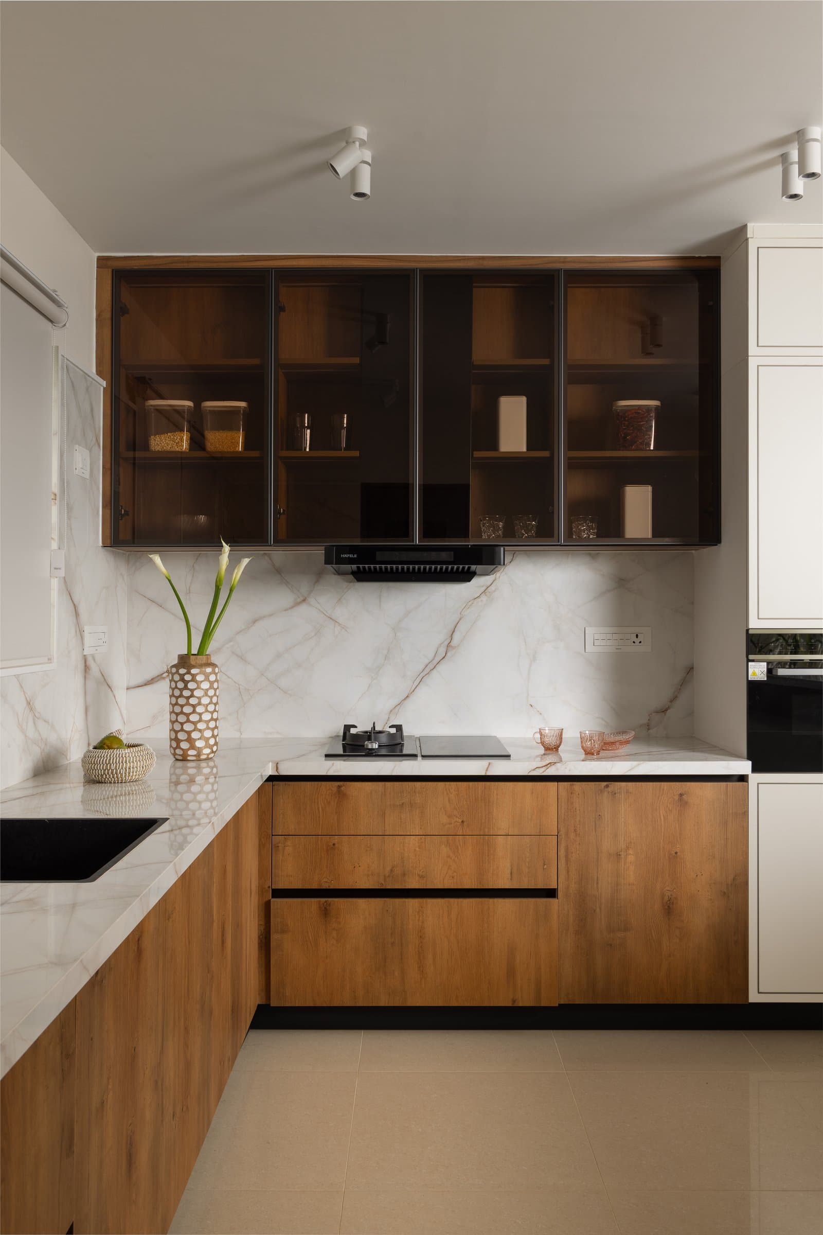 The wet kitchen, where veined quartz and smoked-glass overhead cabinets lend generosity to a compact space