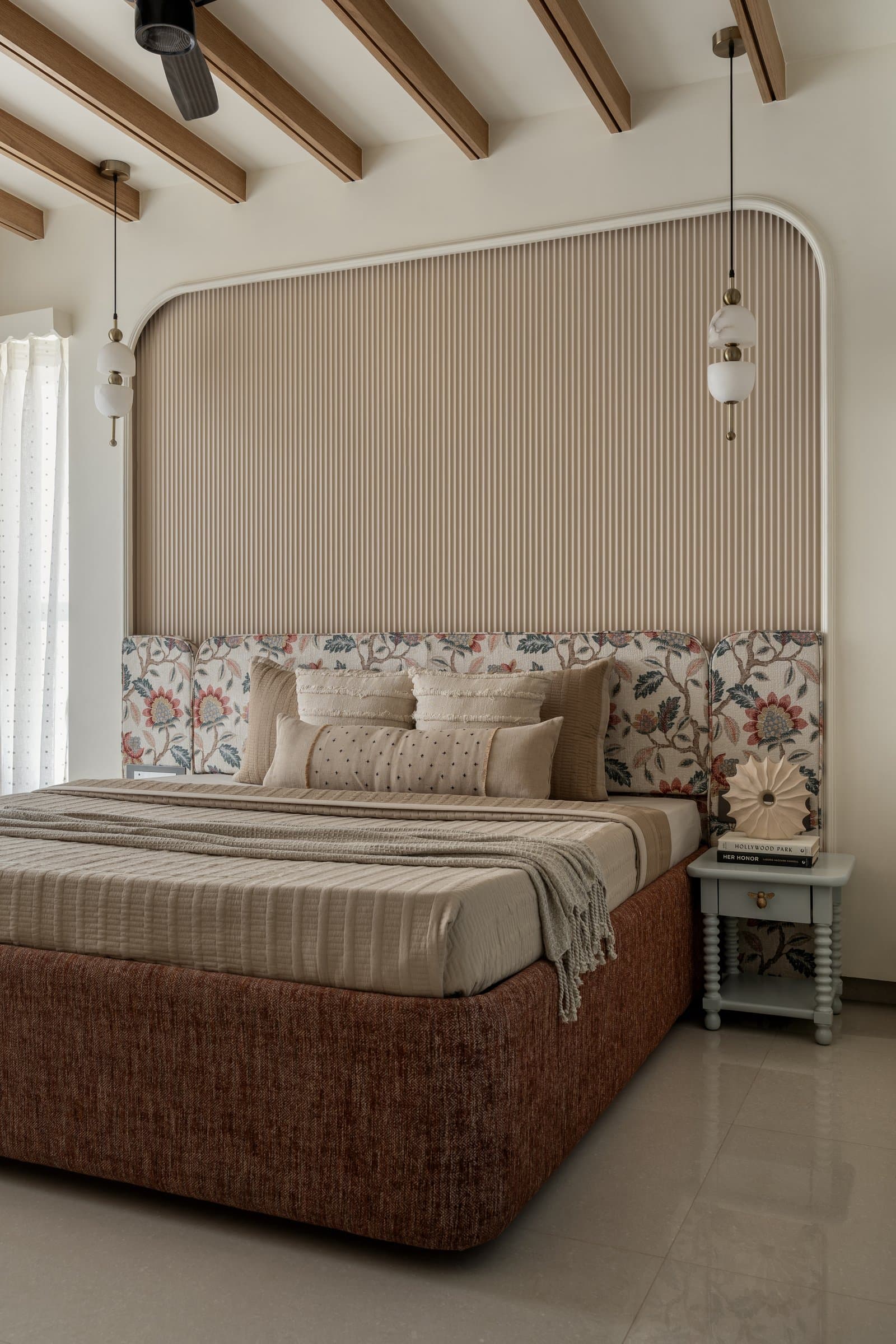 The master bedroom: a fluted oat-toned arch, jacquard side panels, and a rust chenille bed base