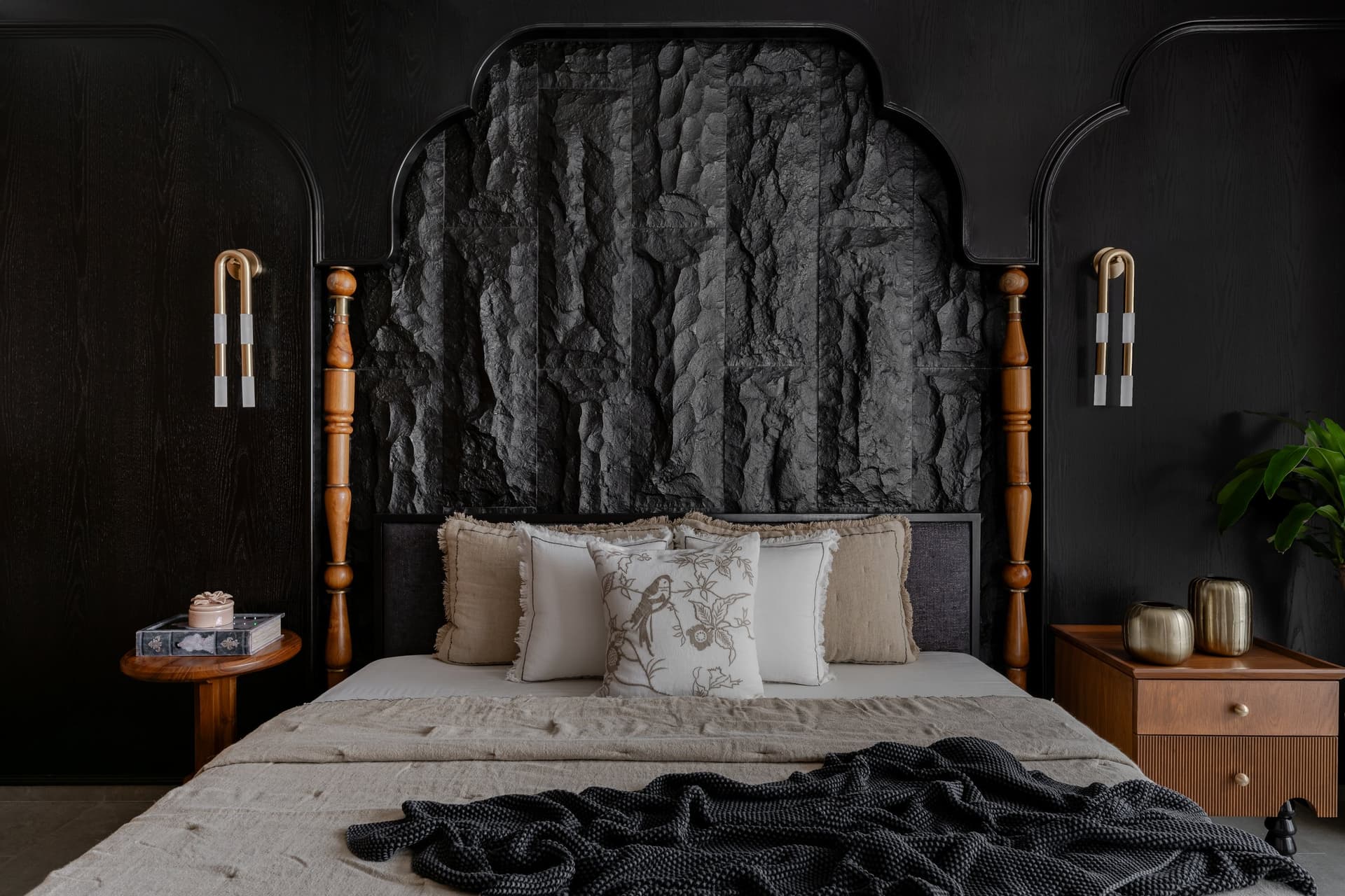 The grandparents' bedroom, where rough-hewn stone fills an arched dark-timber headboard frame