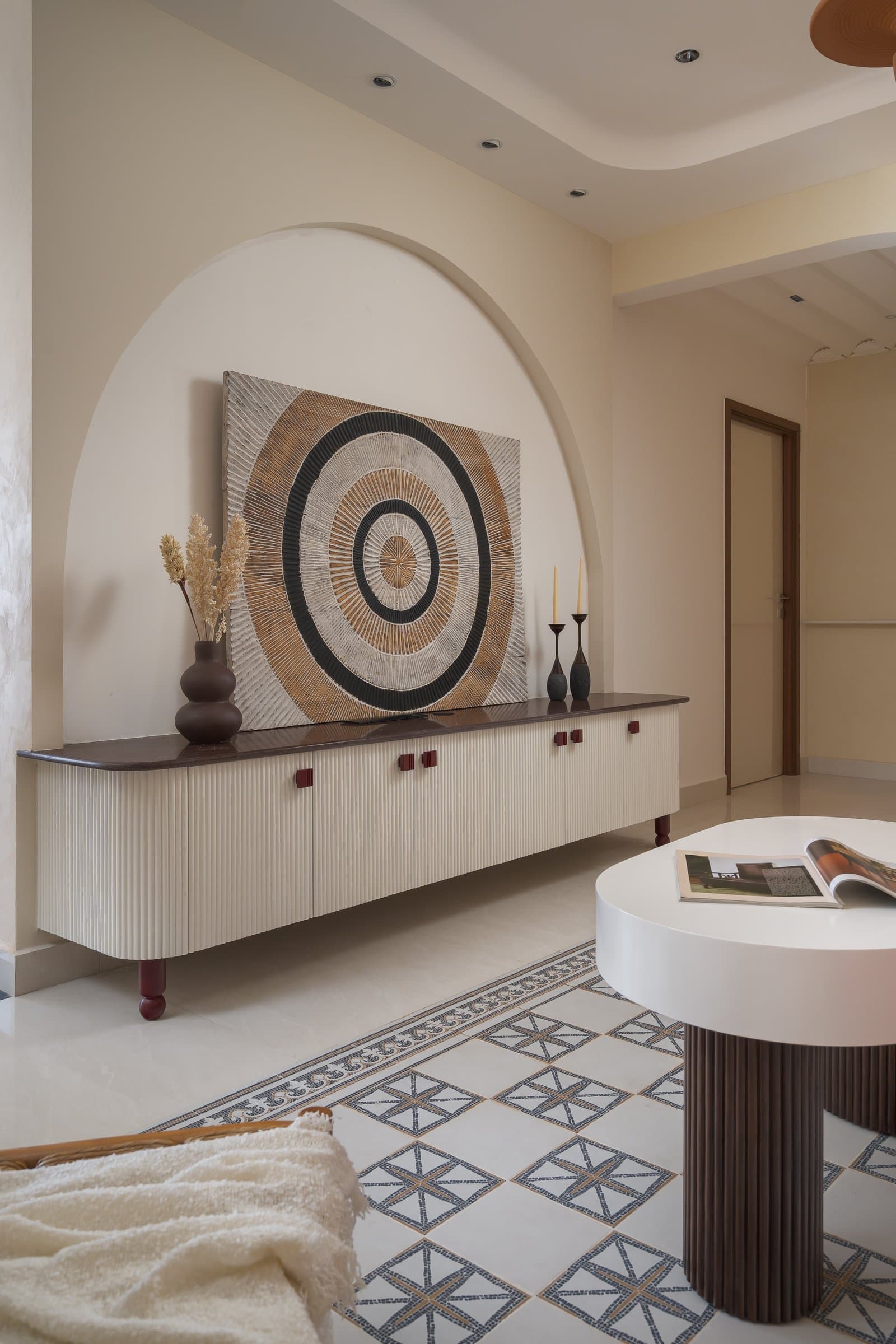 The living room console within its arch, where concentric artwork and fluted cabinetry reinforce the home's circular motifs