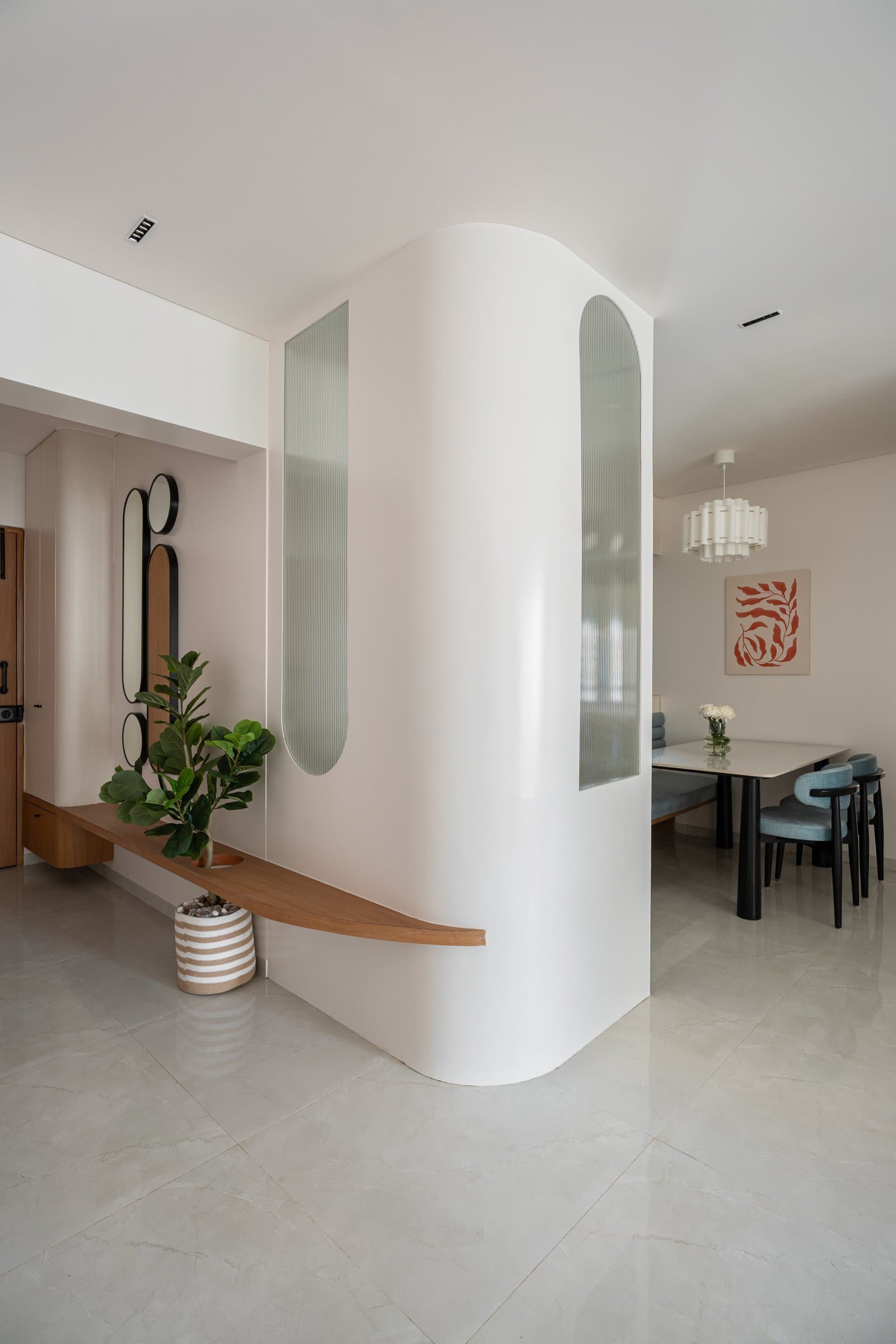 The foyer partition, where fluted glass and a floating timber ledge establish the home's curvilinear vocabulary