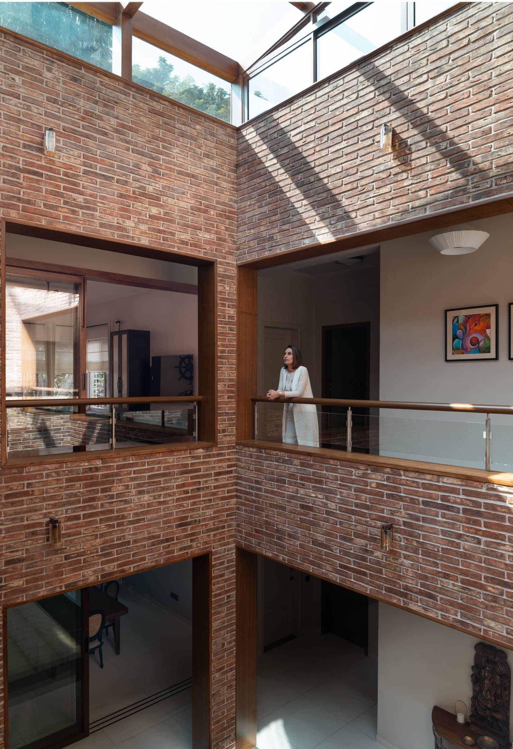 The atrium from the upper walkway: brick, timber-framed openings, and a view down into the living space below