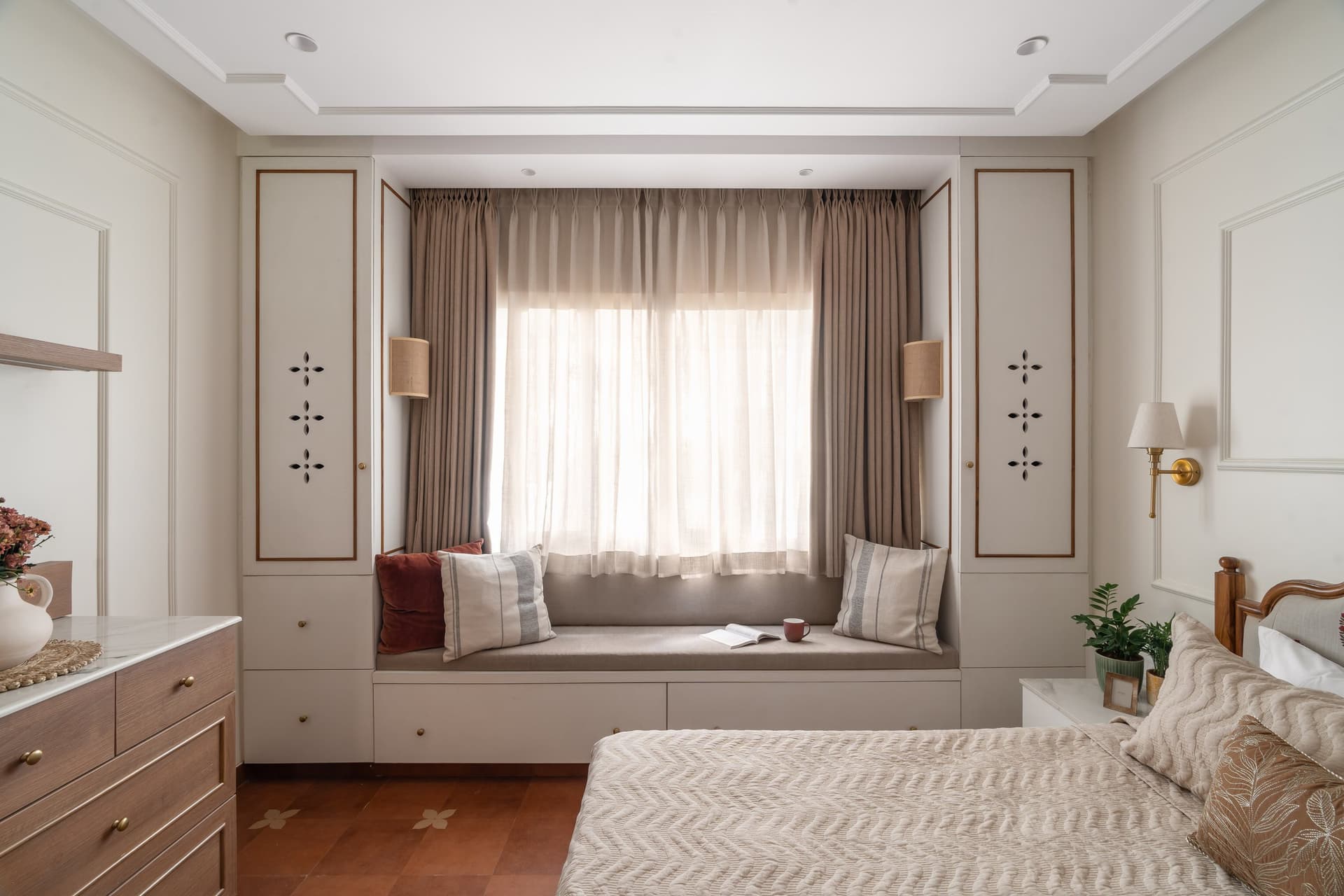 A window seat framed by tall cabinets with brass-trimmed cut-out detailing