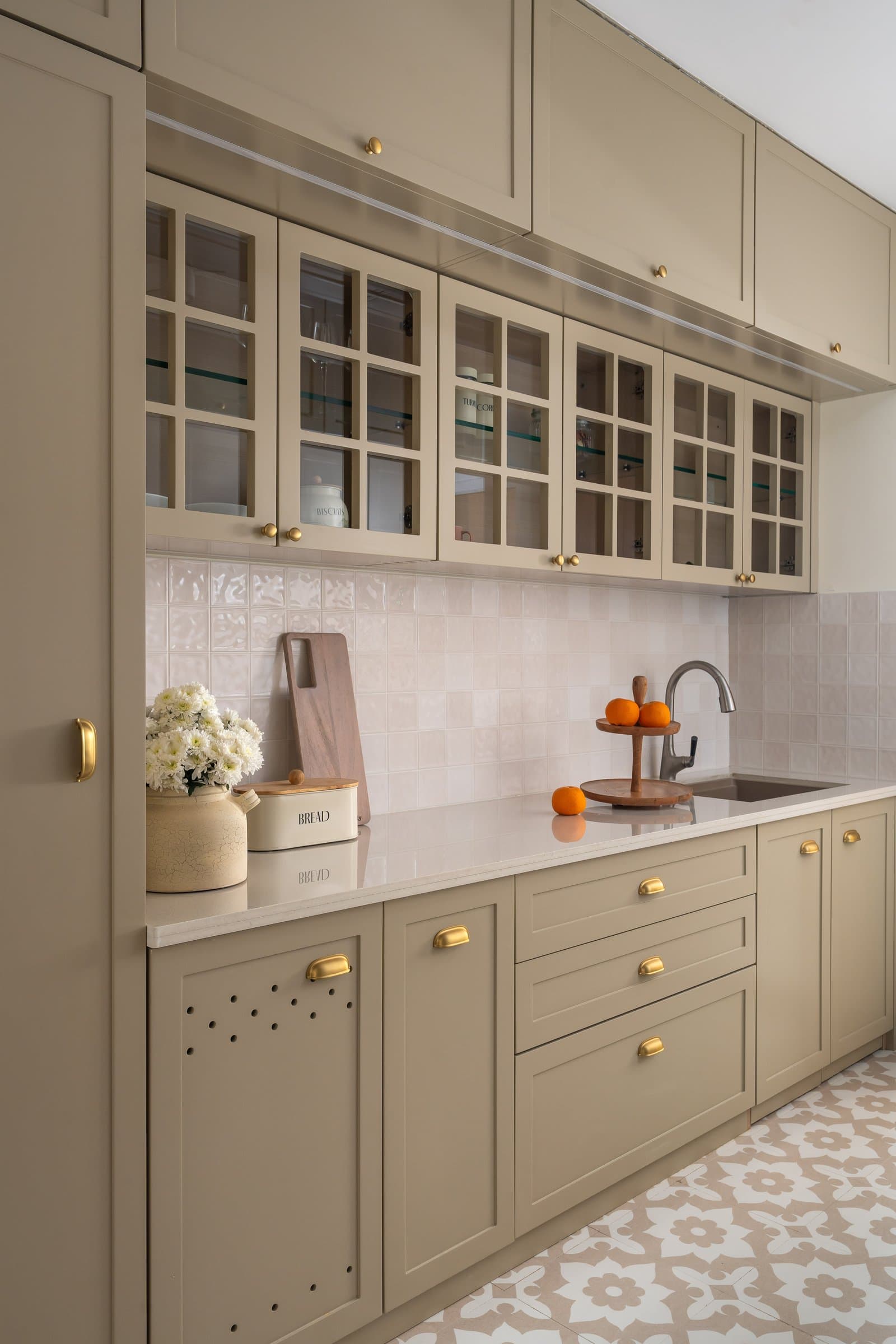 The kitchen in shaker putty and brass, anchored by an encaustic-tiled floor