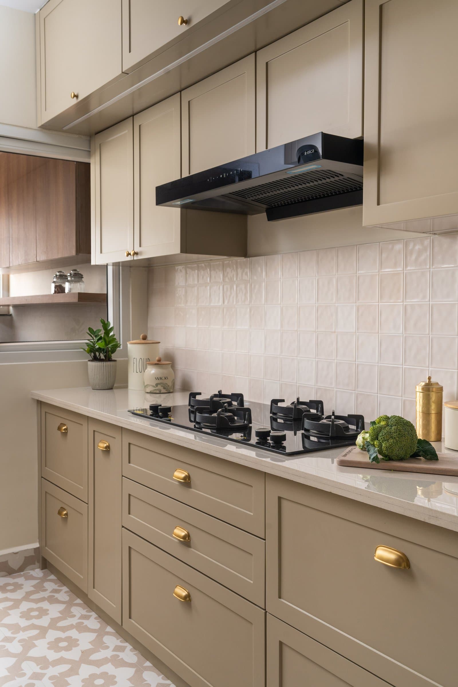 Along the cooking wall, brass hardware catches light against muted cabinetry