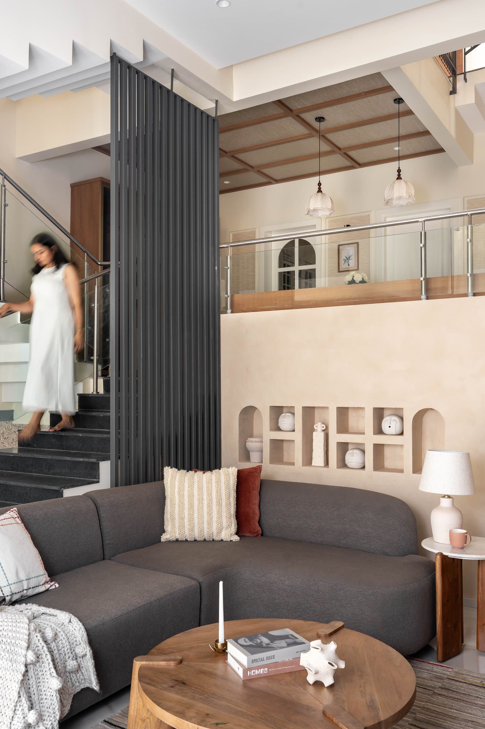 The double-height living room, where a slatted screen filters the staircase without sealing it off