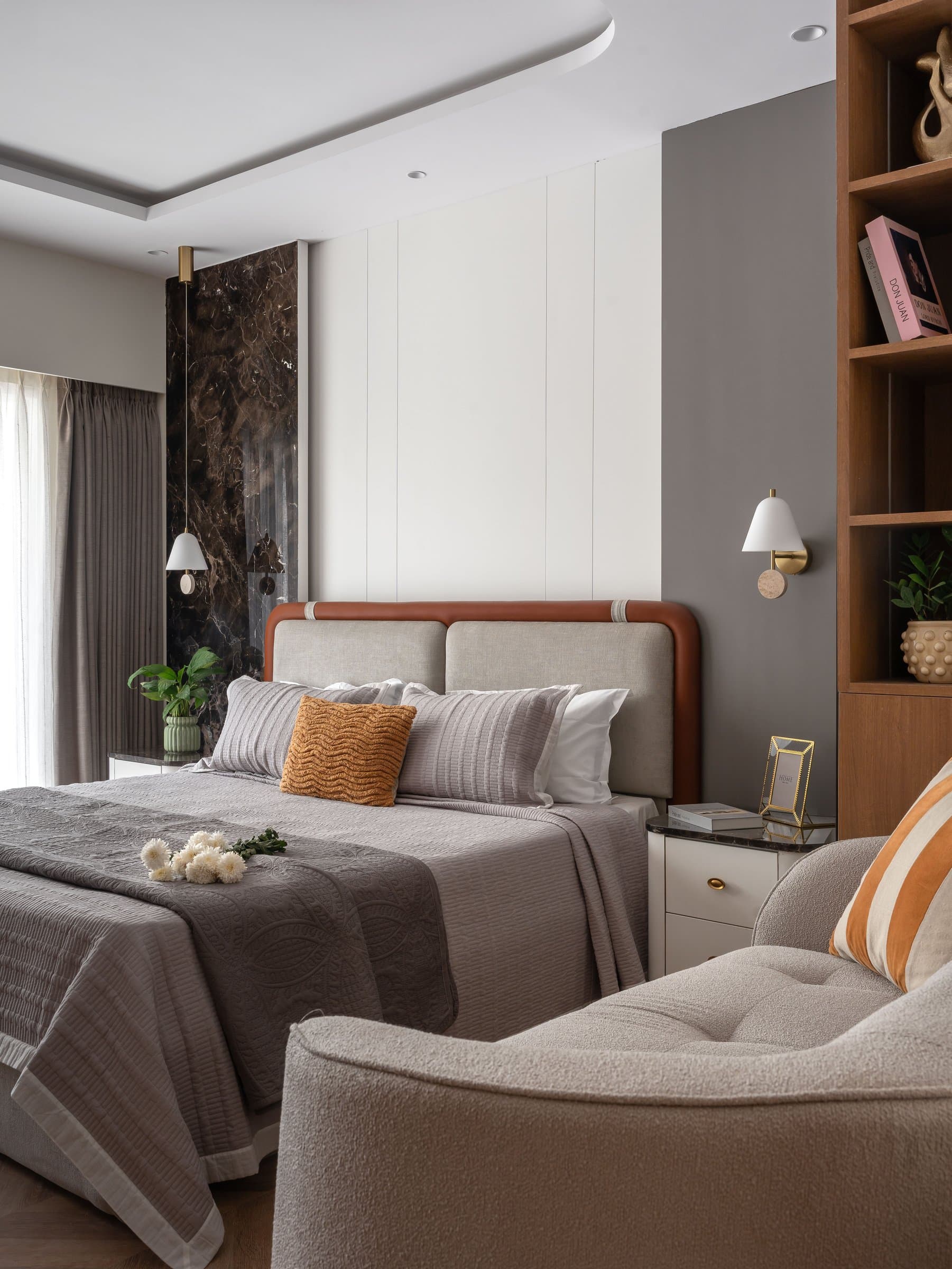 The master bedroom: a dark marble slab and a column of warm wood shelving frame an upholstered headboard
