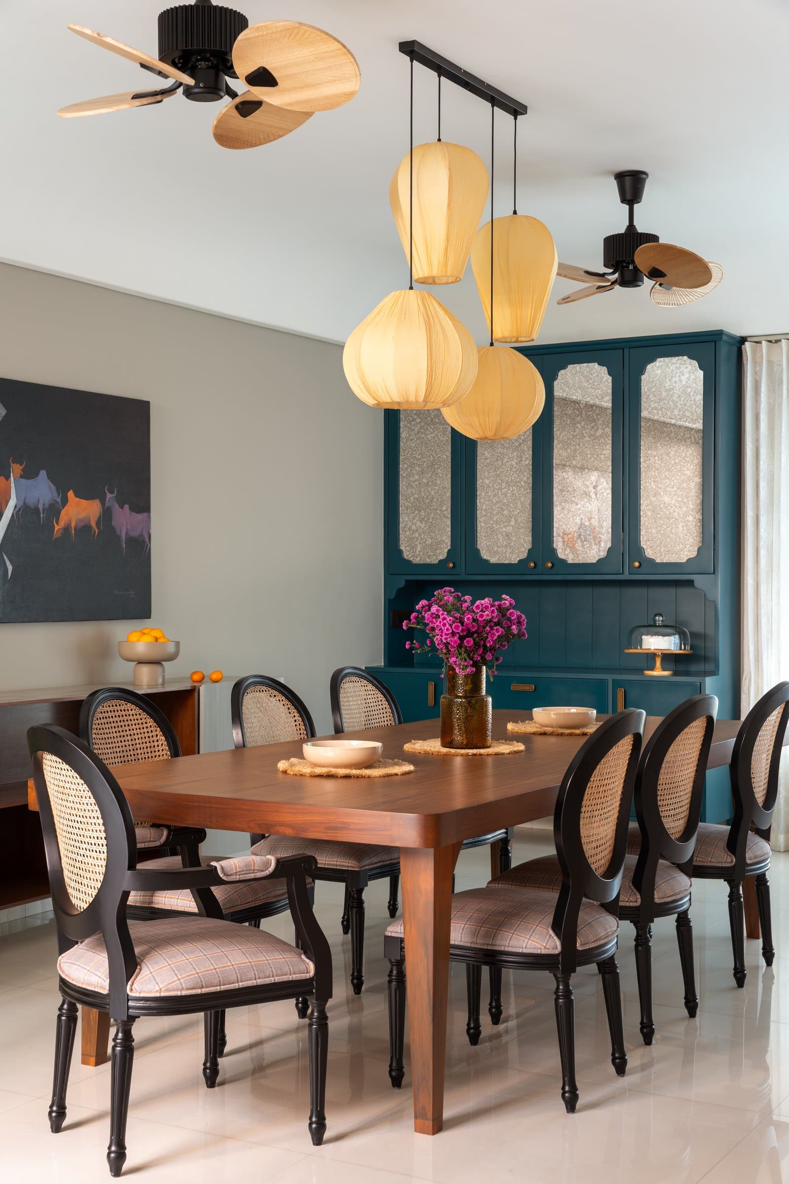 The dining room: a deep teal cabinet and organic fabric pendants anchor a room built for generous gatherings