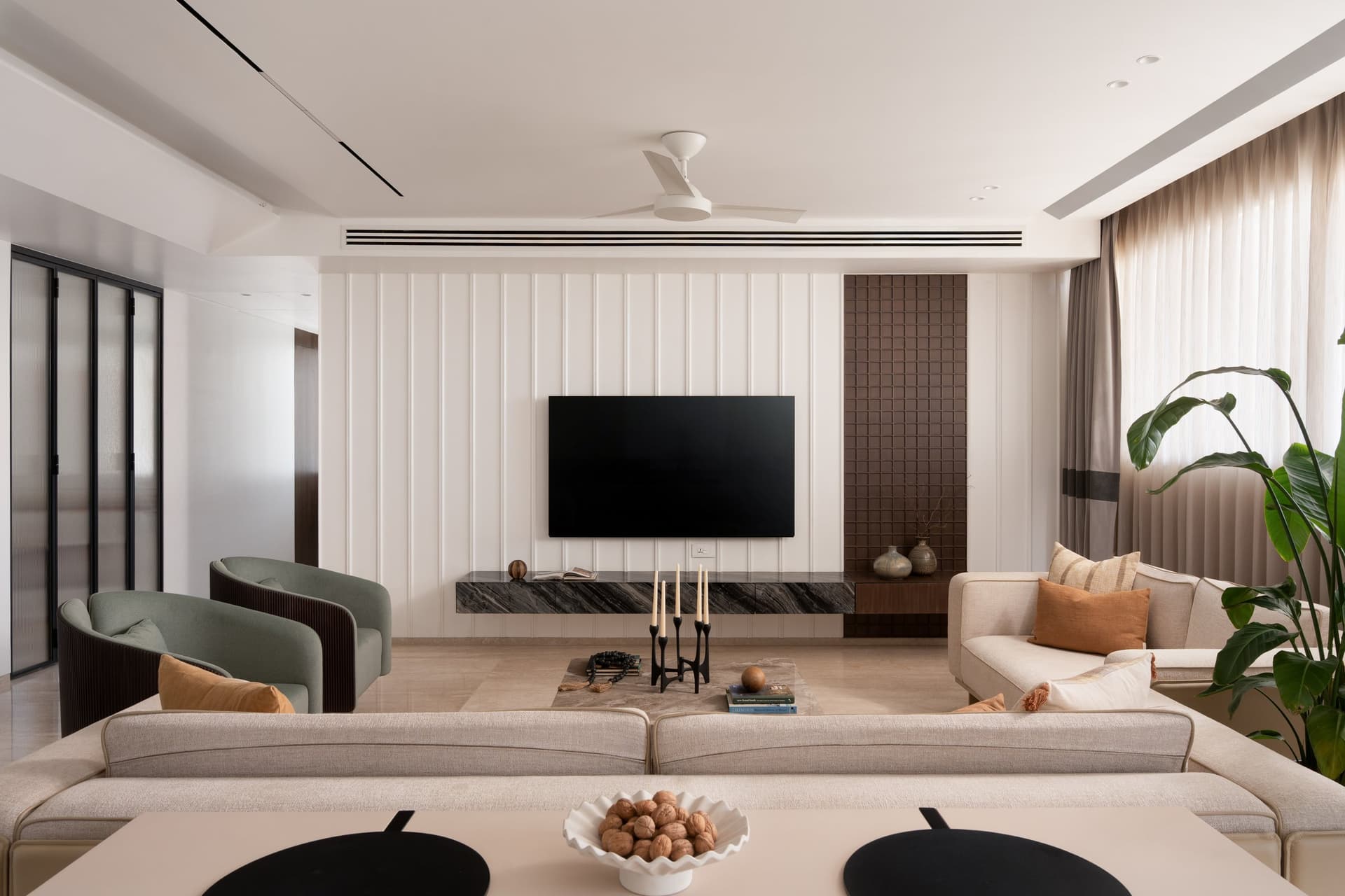 The living room: a fluted media wall in cream, inset with a slim panel of woven oak