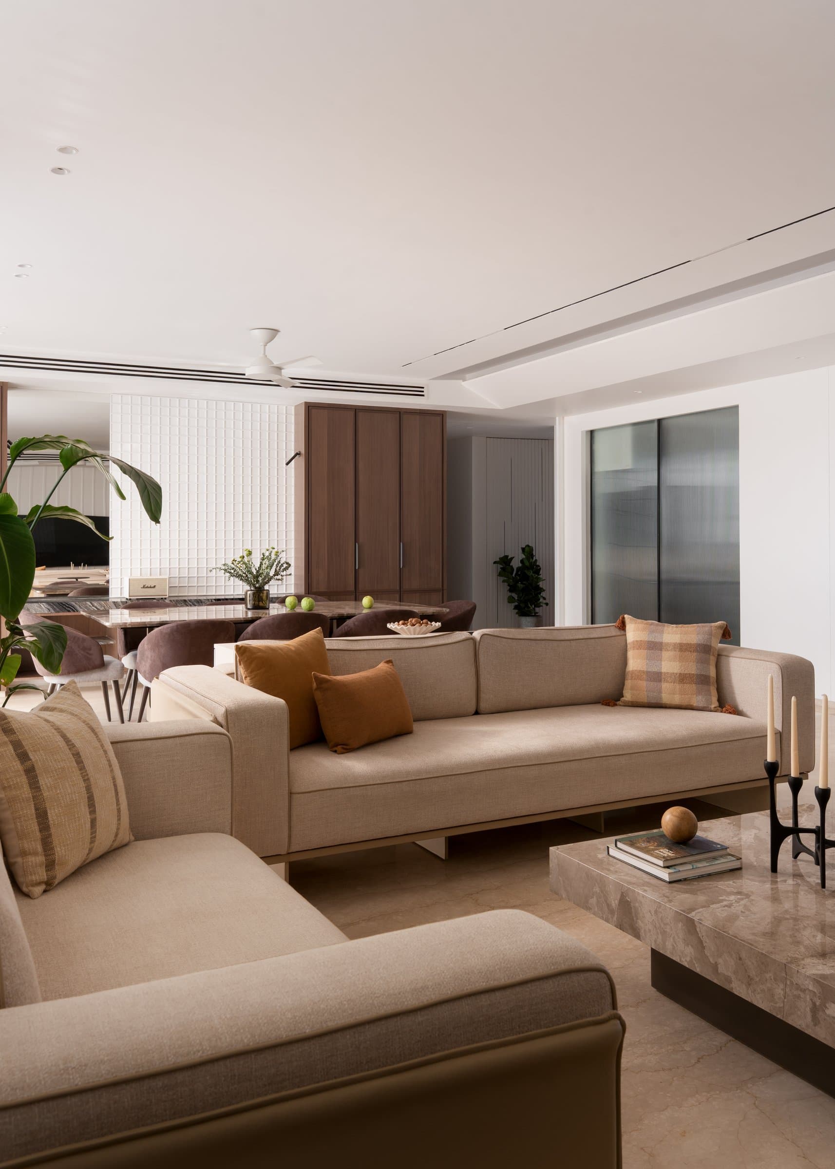 Looking back across the living room, with its linen sectional, stone coffee table, and blackened-metal candelabra