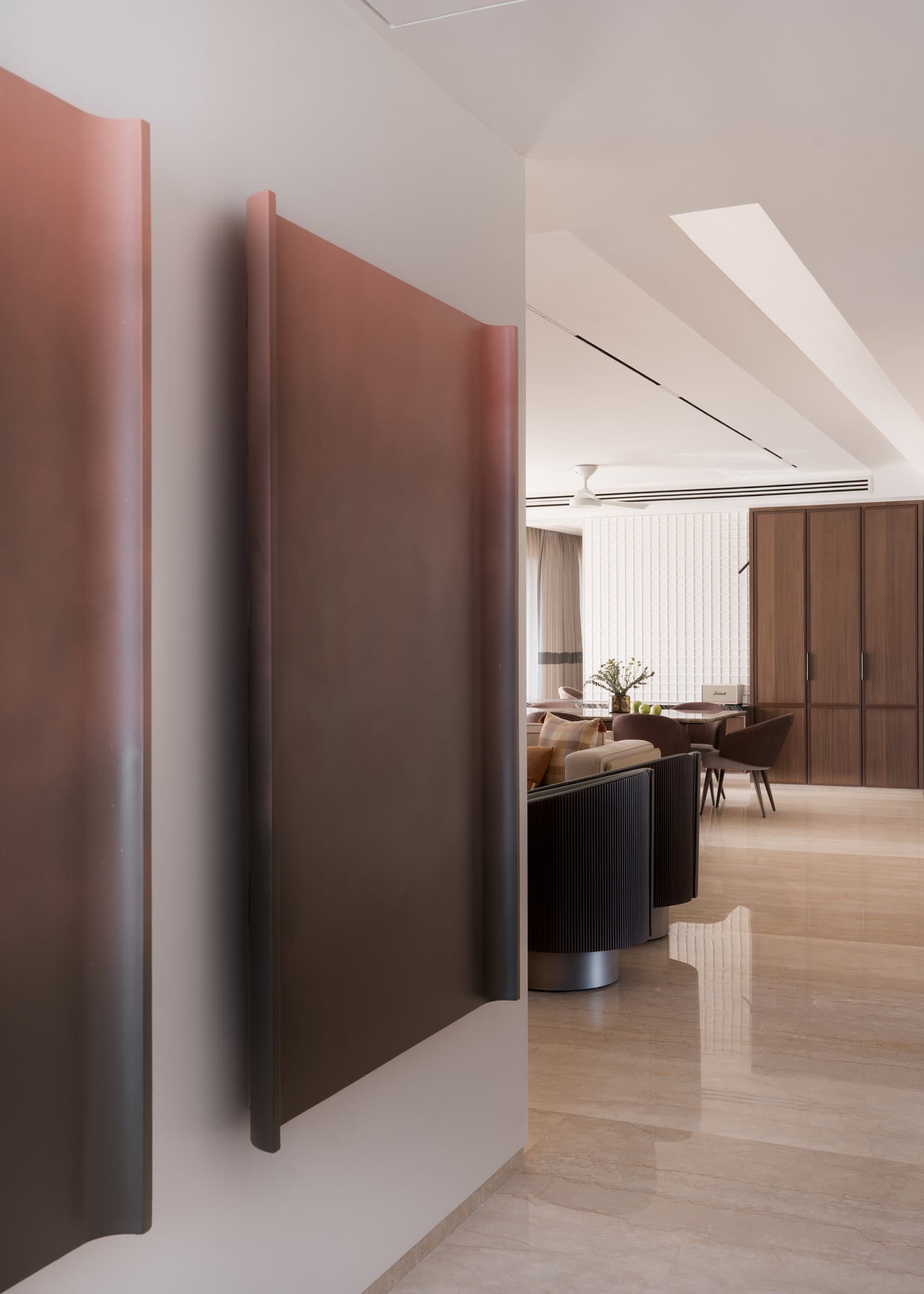 The threshold to the living room, marked by a leather-clad pivoting panel in oxblood, the public realm's single assertive note