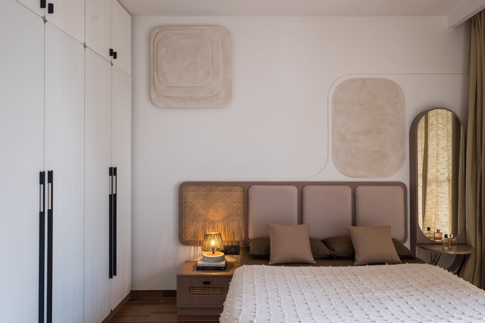 Two soft plaster reliefs above a headboard wall, where storage, art and architecture speak the same language