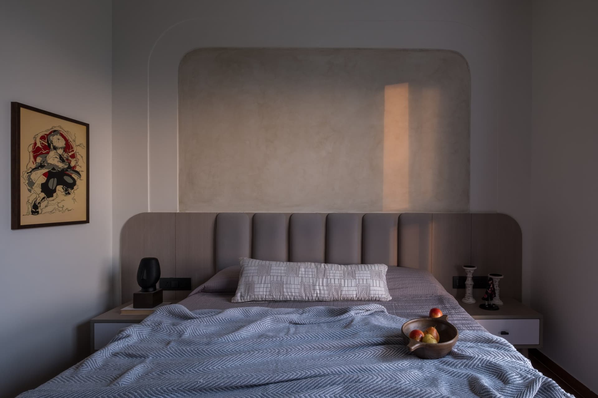 The second bedroom, with a channel-tufted headboard set beneath a softly plastered arched panel