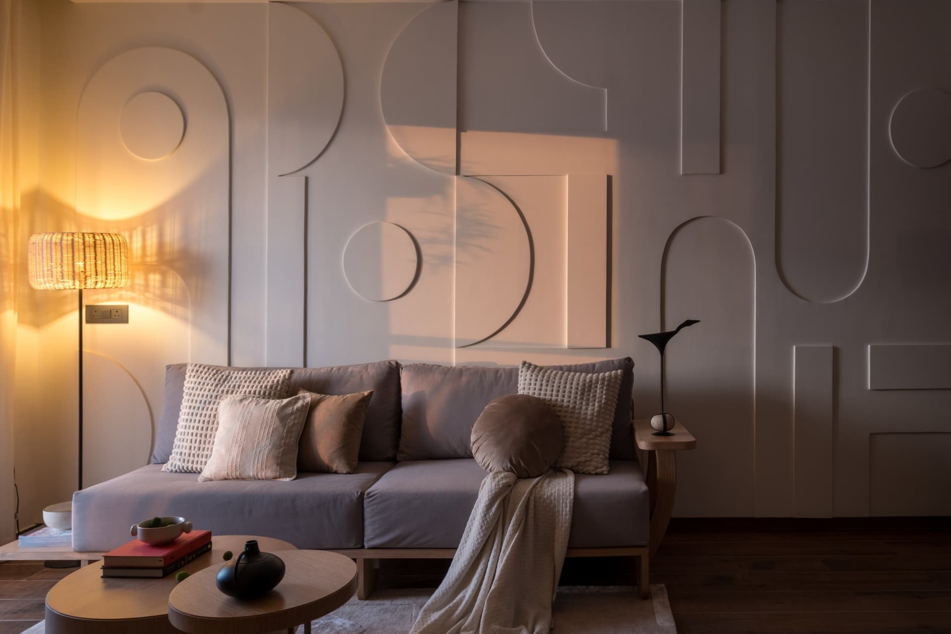 By evening, the same relief wall turns atmospheric under the warm glow of a rattan floor lamp