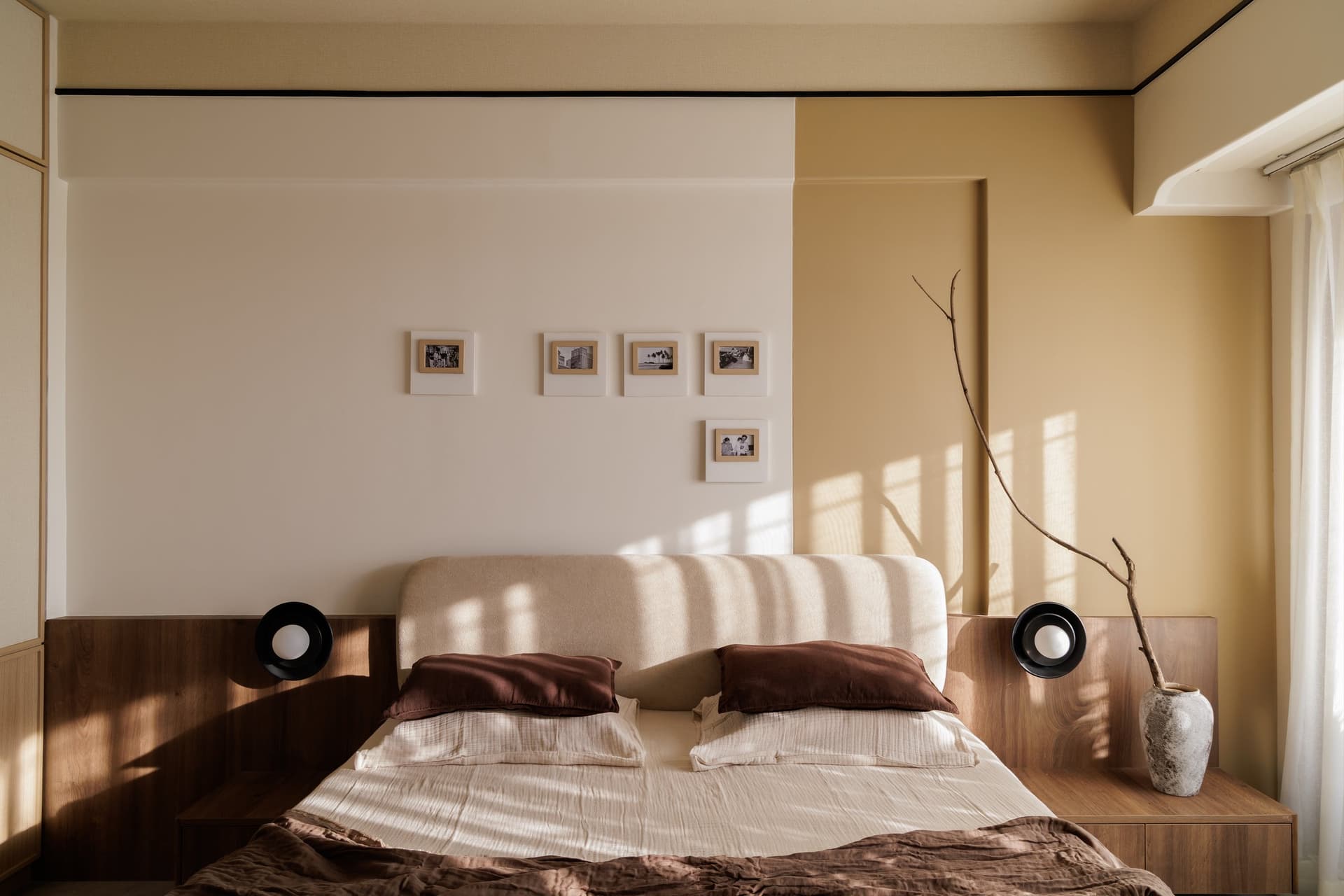 The bed seen straight-on, where the headboard's curve plays against strict horizontal trim