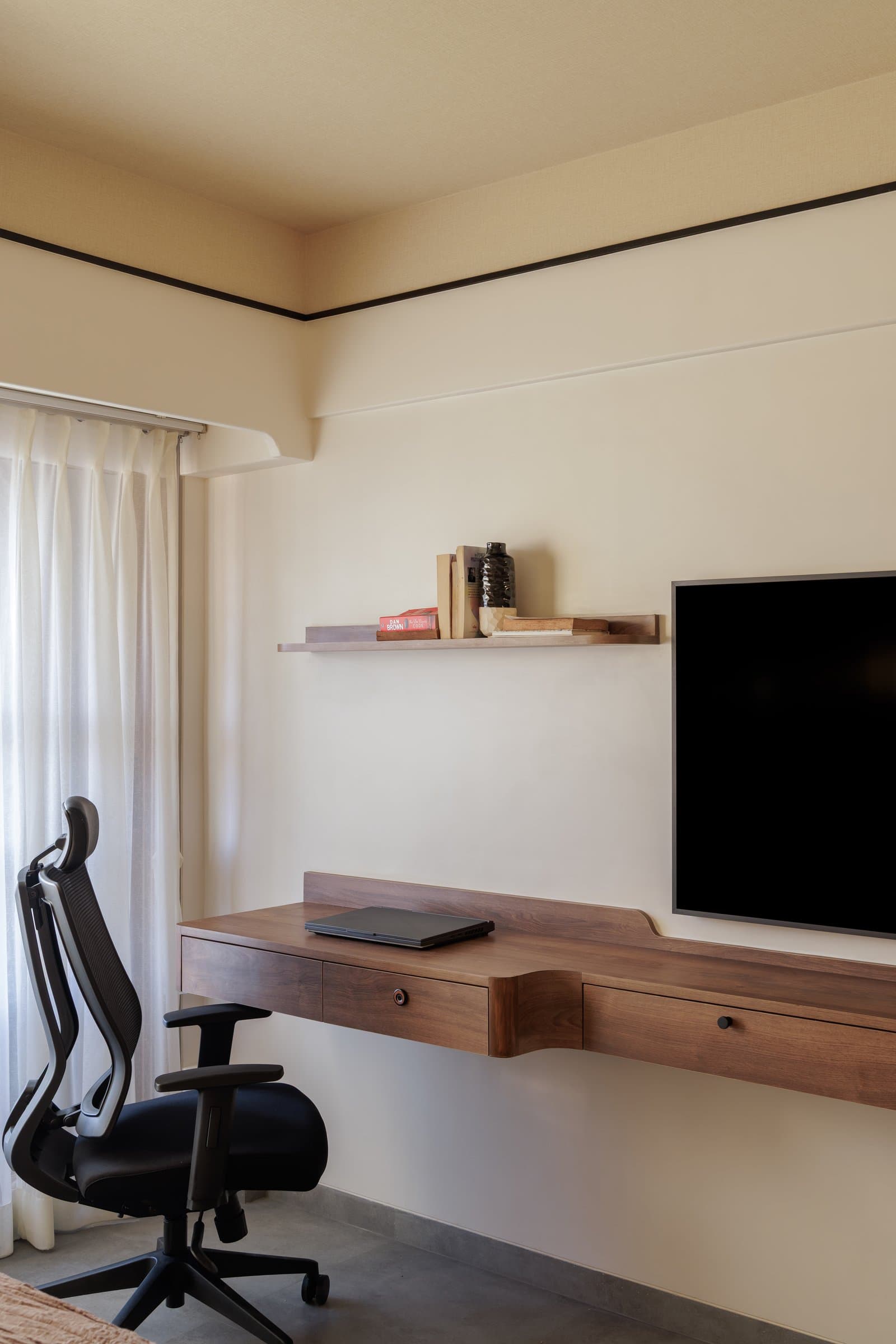 A study niche tucked into the bedroom: a stepped walnut desk under a floating shelf