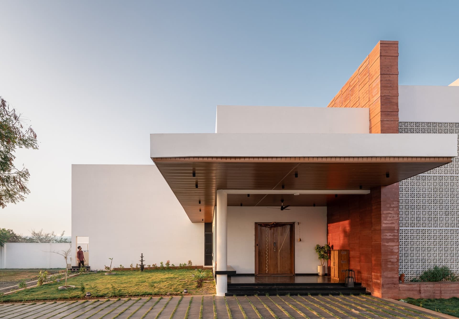A wider view of the front facade, where staggered white volumes and sandstone verticals create rhythm without ornament