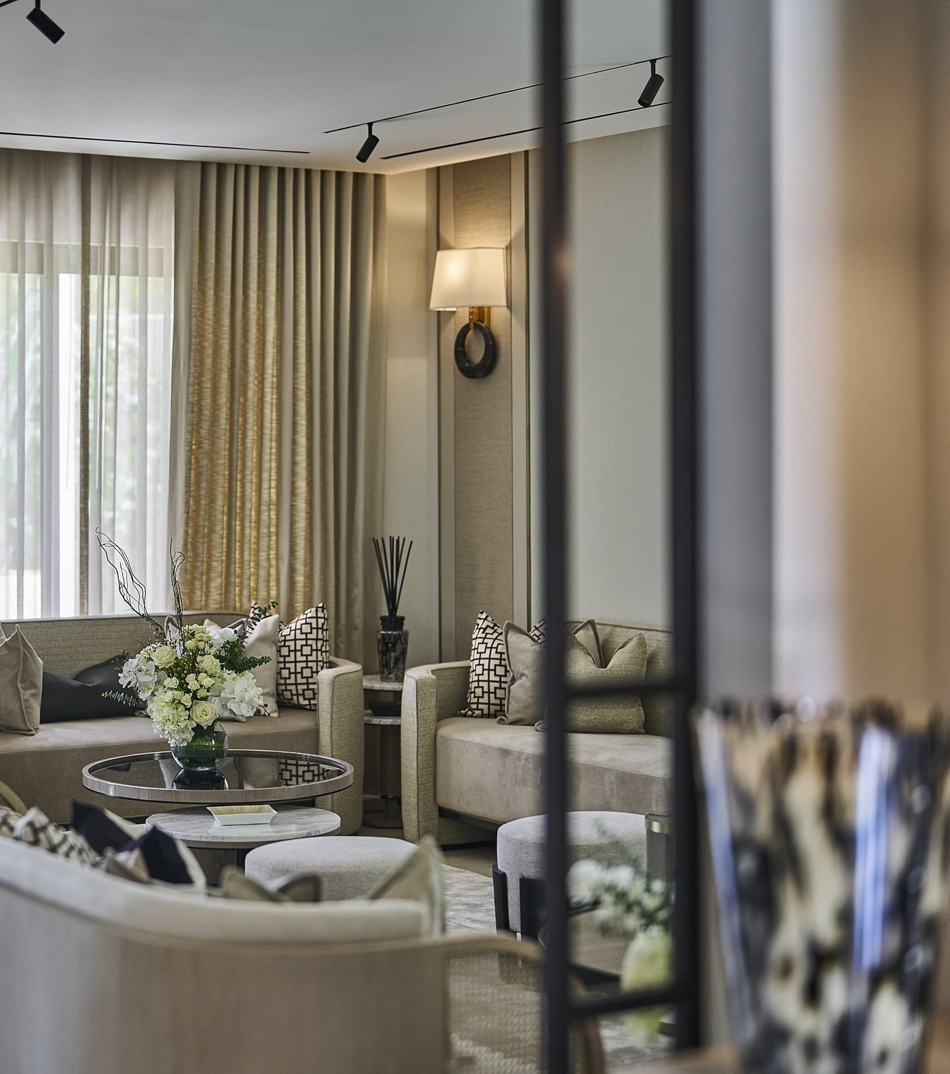 The formal lounge, where layered drapery and a sculptural sconce establish the home's quiet register