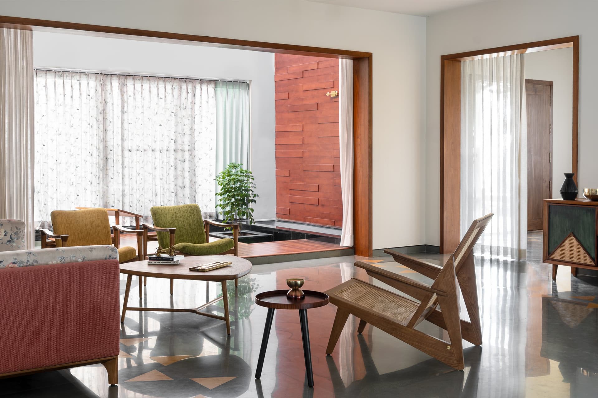 The living room's relationship to the courtyard, sandstone visible through glazing, bringing warmth into a neutral interior