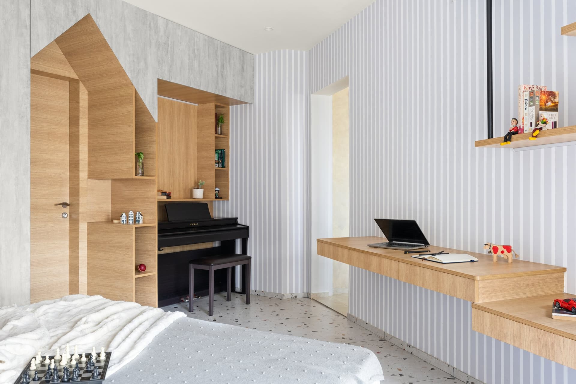 The piano nook returns the house silhouette as a built-in motif