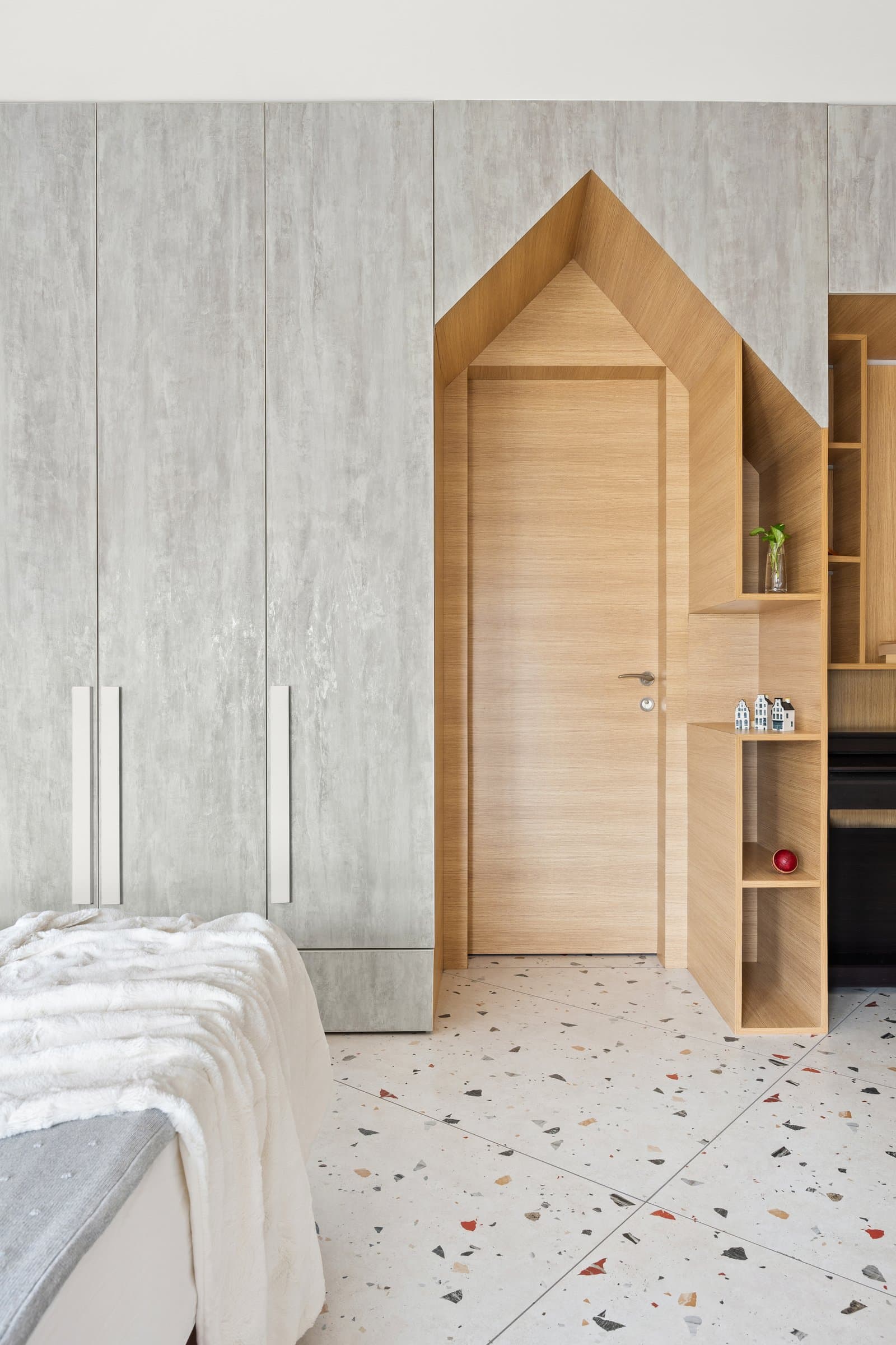 A pitched-roof opening cut into the wardrobe wall turns a routine threshold into the room's visual anchor