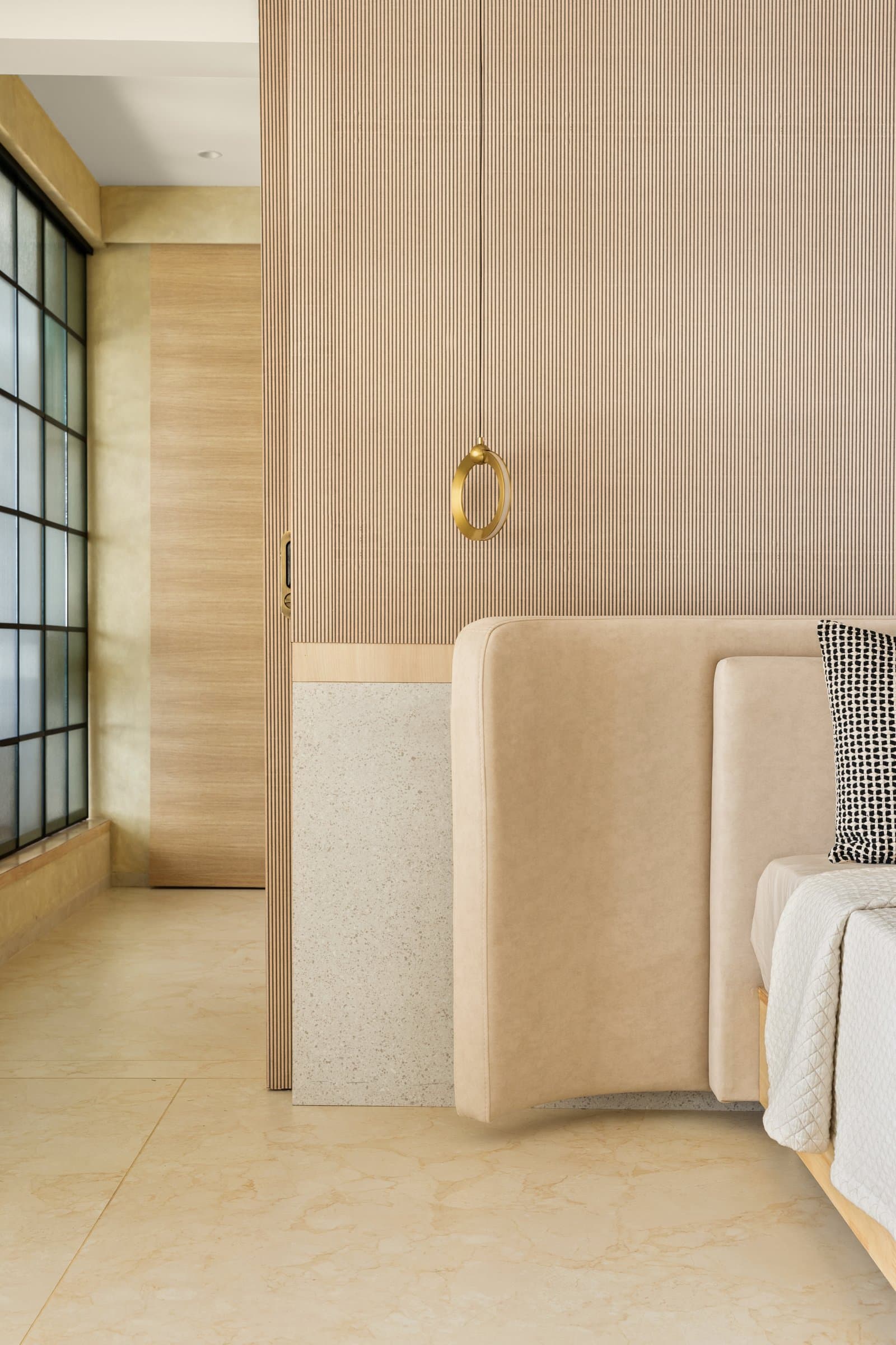 The headboard wall in close range, where brass becomes the room's signature