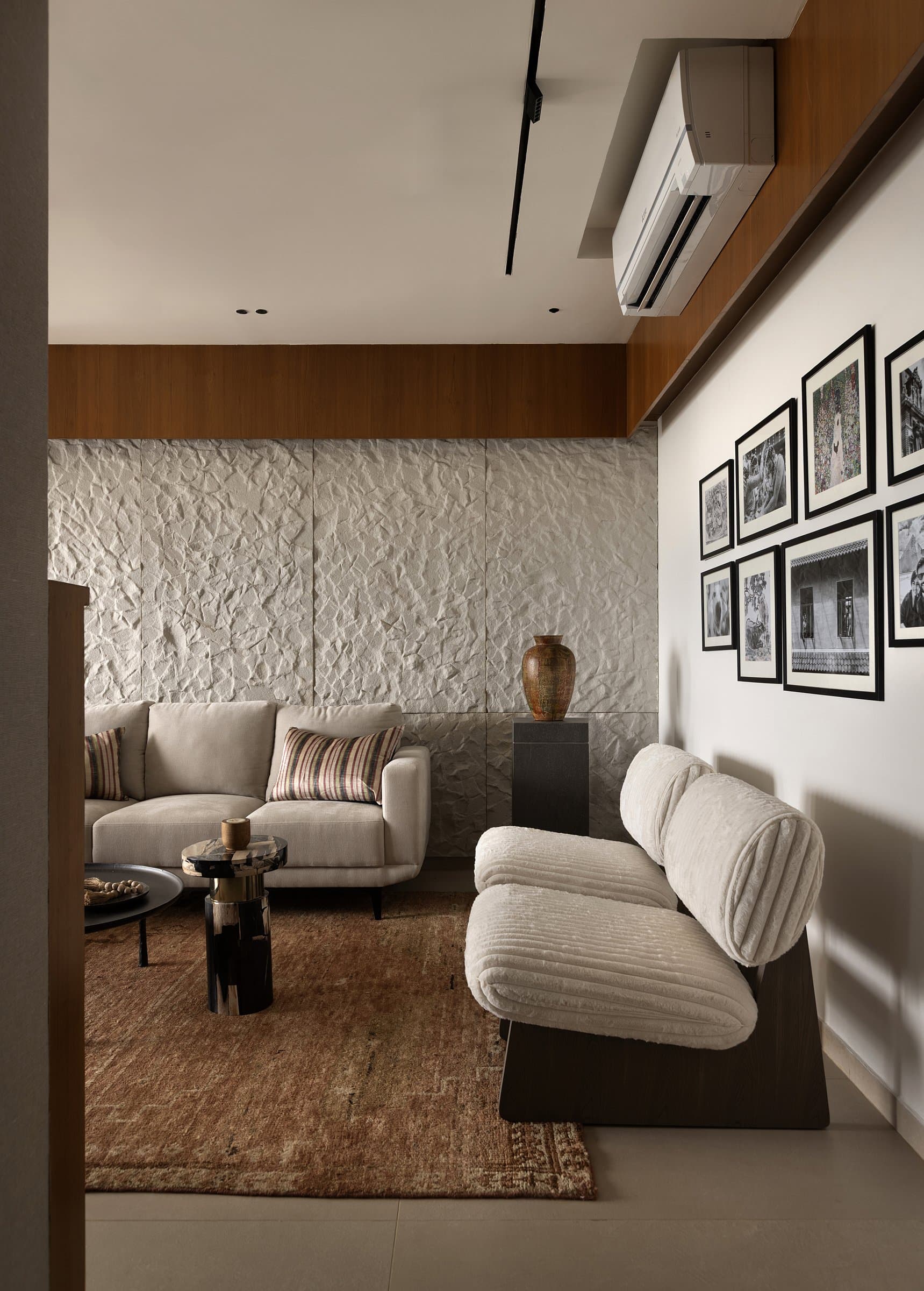 Cream boucle lounge chairs sit beneath a salon wall of black-framed photographs, biography introduced without sentimentality