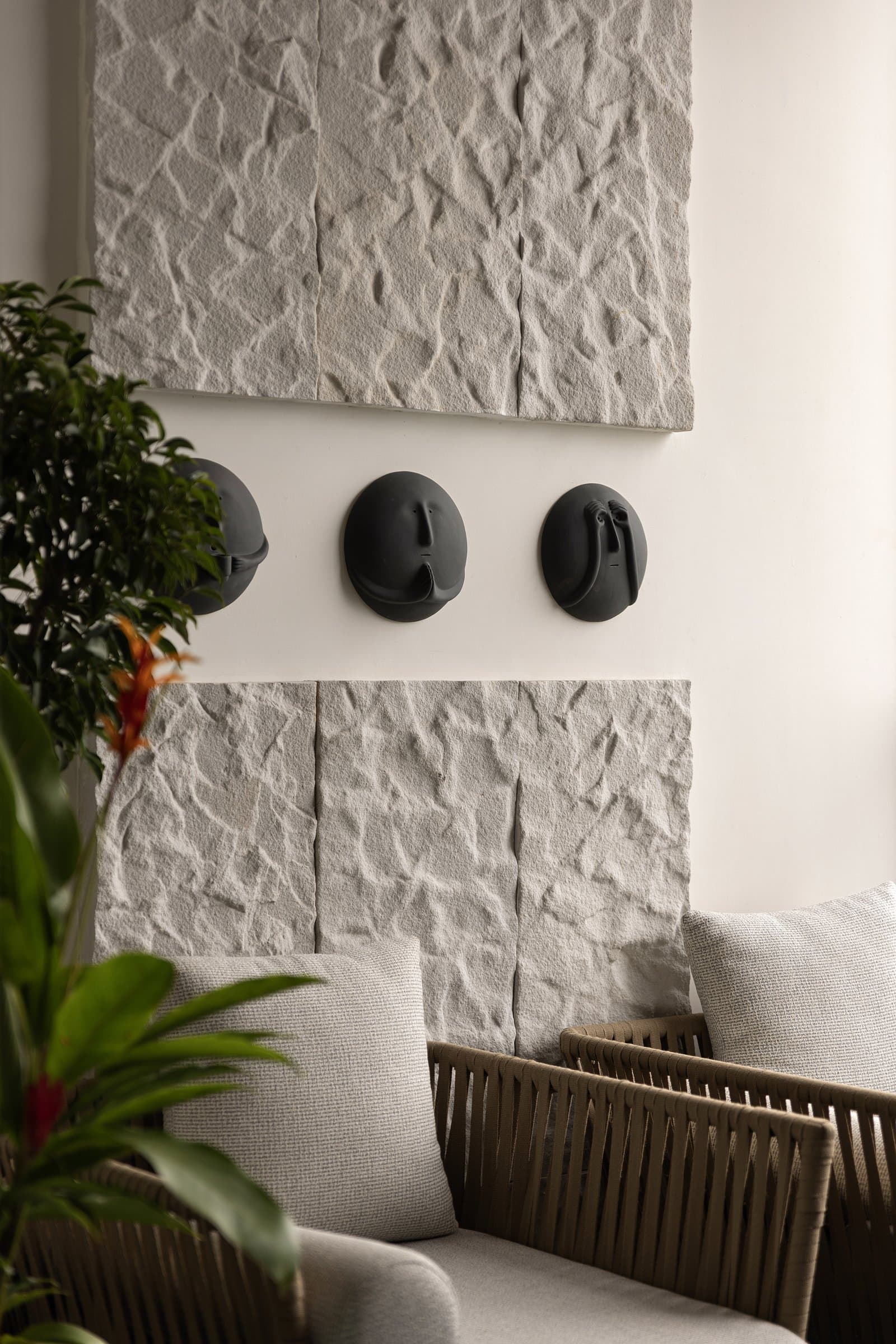 Claymen's matte black faces sit between two sandstone panels, the studio's instinct for material economy made visible