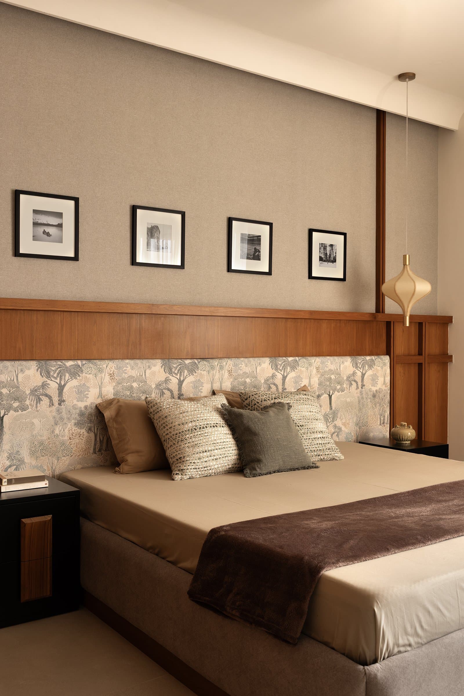 The master bedroom, where a printed forest scene wraps the bed in painterly landscape above warm veneer