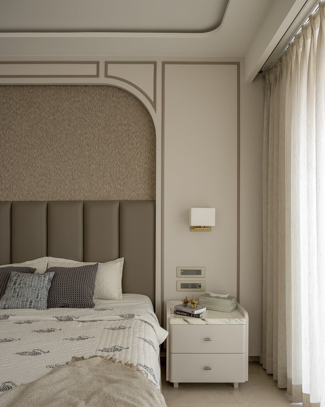 A third bedroom where a dual-material arched headboard carries the room's expressive weight within painted moulding