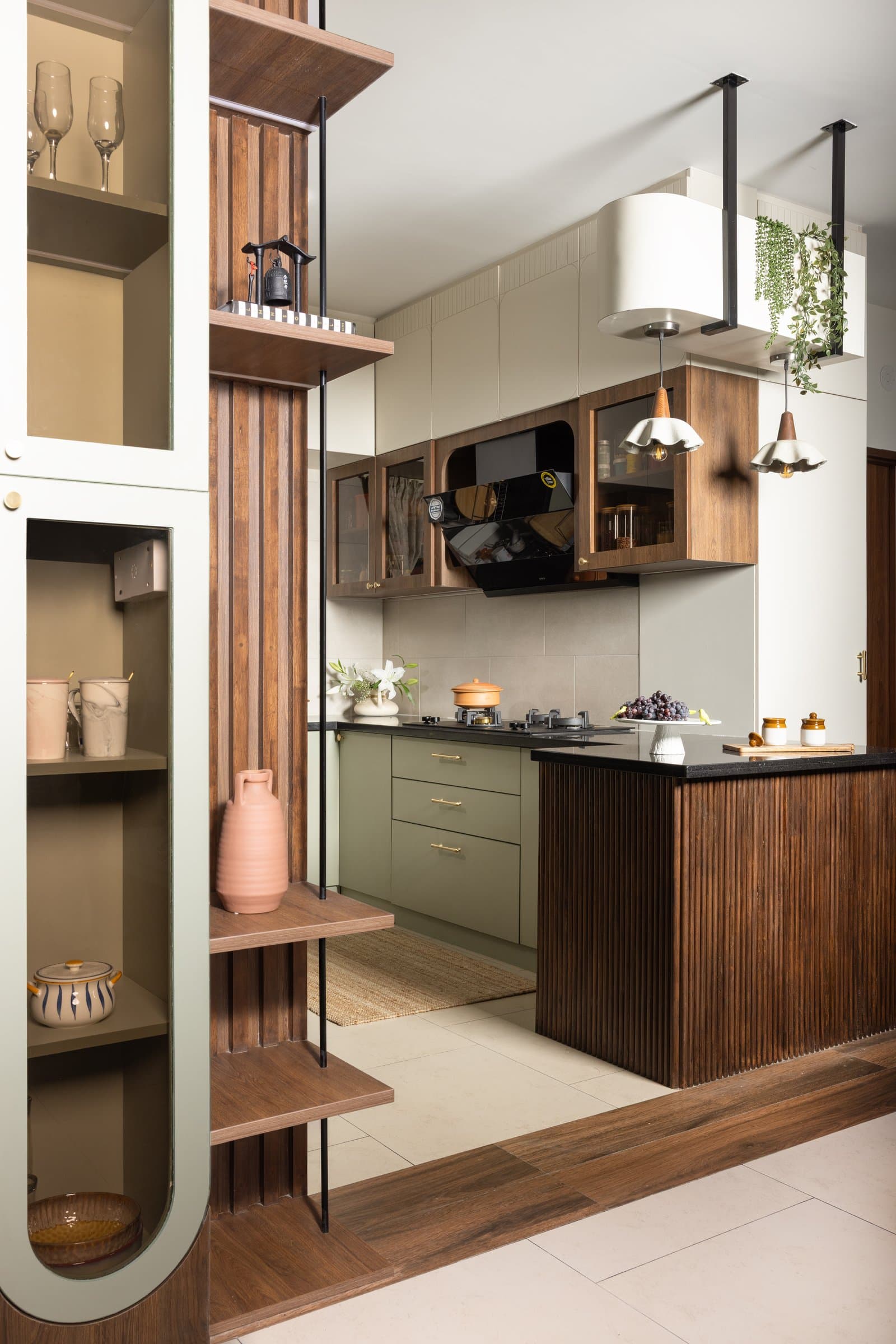 The kitchen, where olive cabinetry, a fluted walnut island, and a slatted partition mediate rather than separate