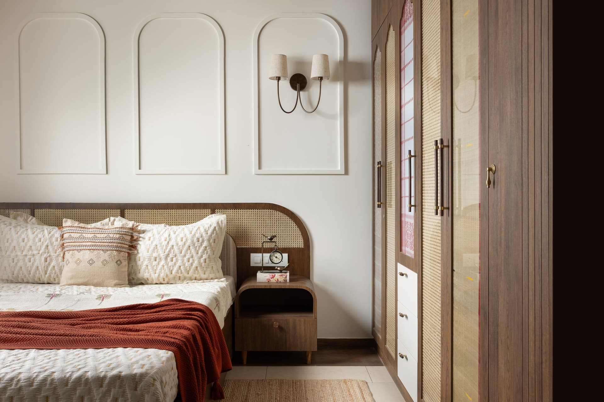 In the master bedroom, recessed arched mouldings and a curved cane headboard introduce the home's recurring vocabulary of arches and woven panels