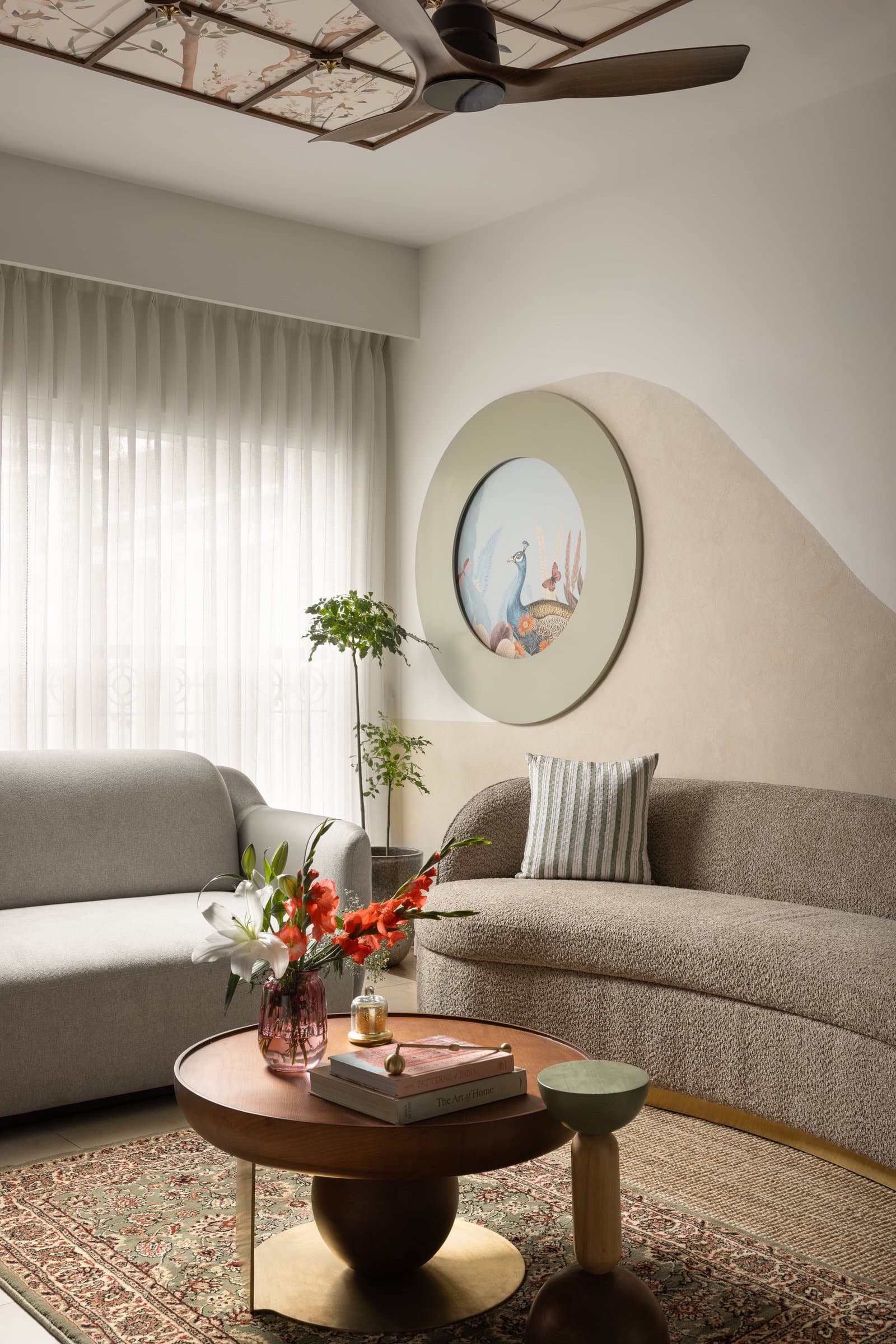 The second seating zone, where curved boucle sofas and a circular peacock medallion shift the register from conversation to stillness