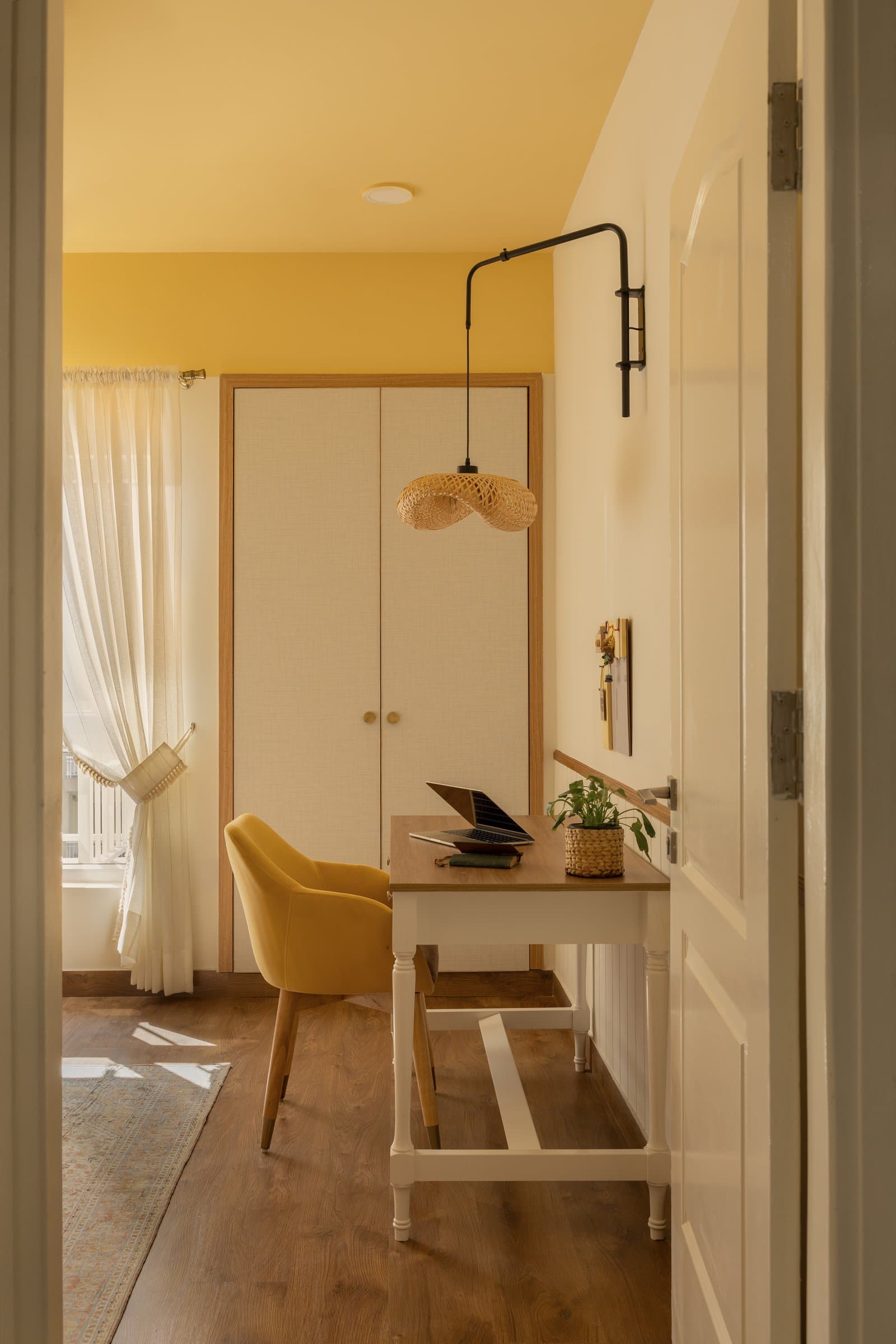 The study, energised by a sunshine-yellow ceiling, with a woven pendant and fabric-panelled wardrobe