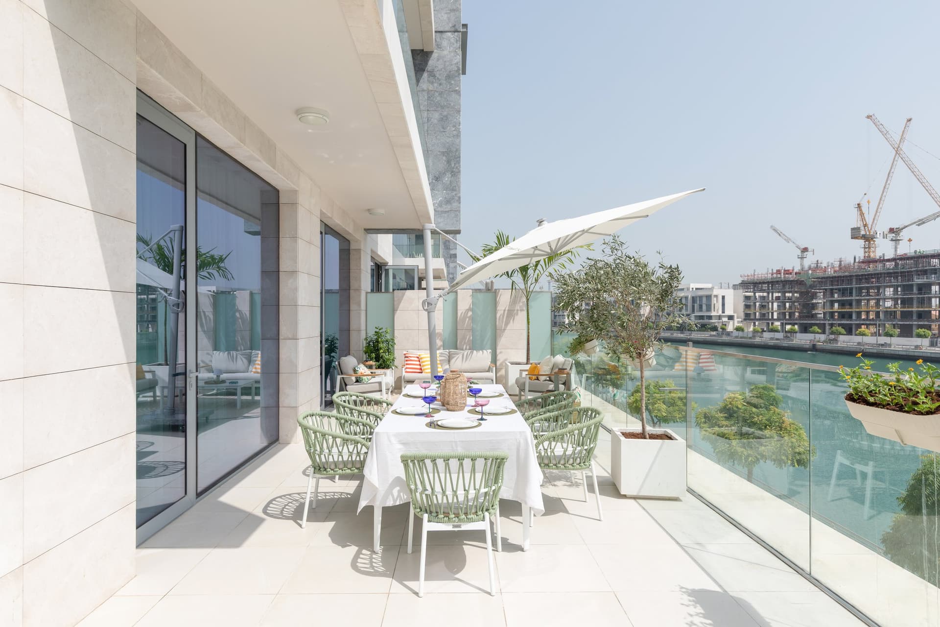The terrace dining setting, with rope-back chairs in a sage that picks up the canal water below